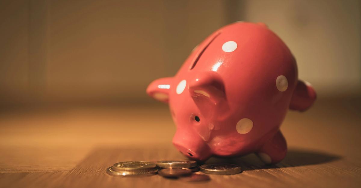 Pink piggy bank with polkadots with nose tilted towards change by Andre Taissin.