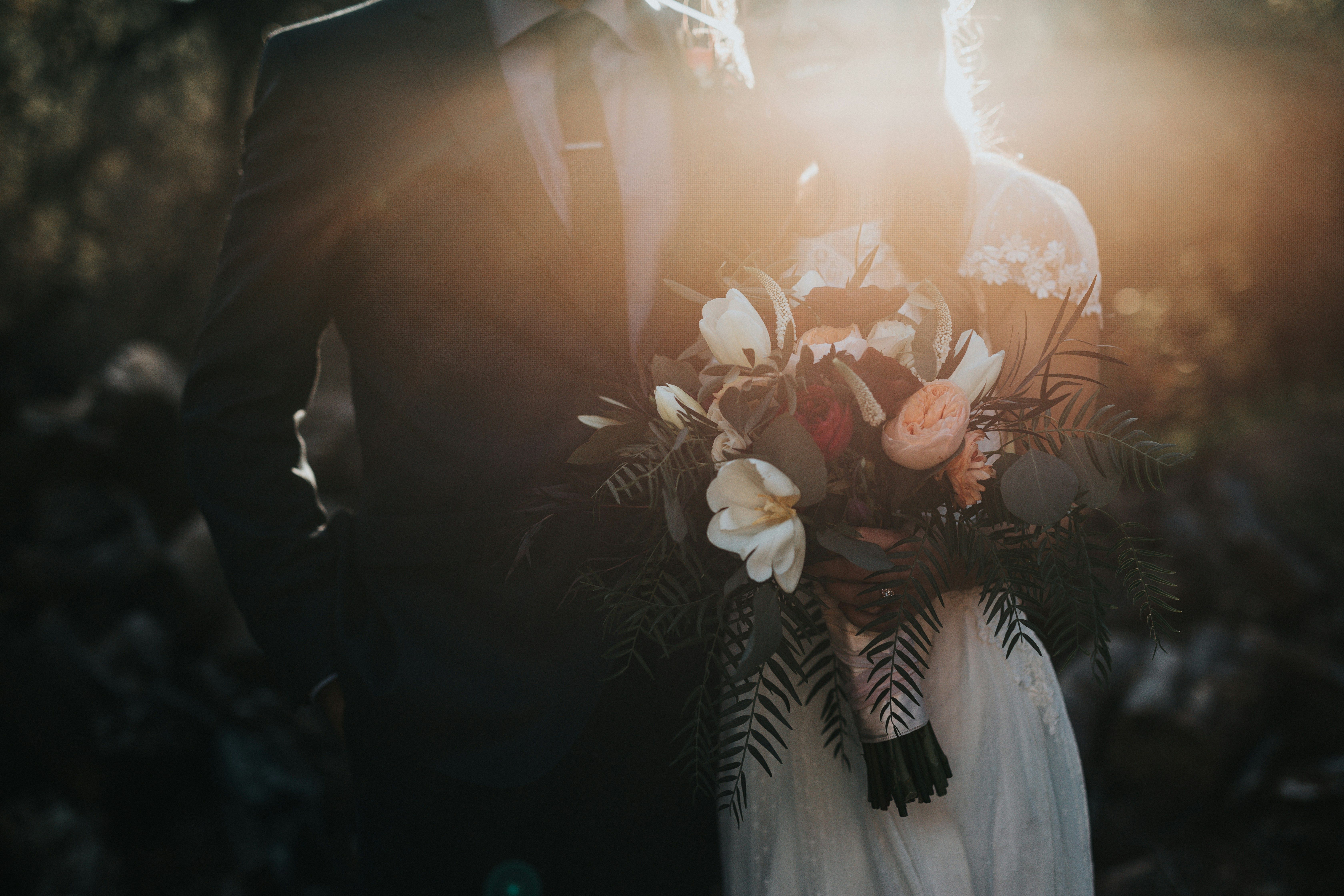 Newly wed couple with wife holding flowers.