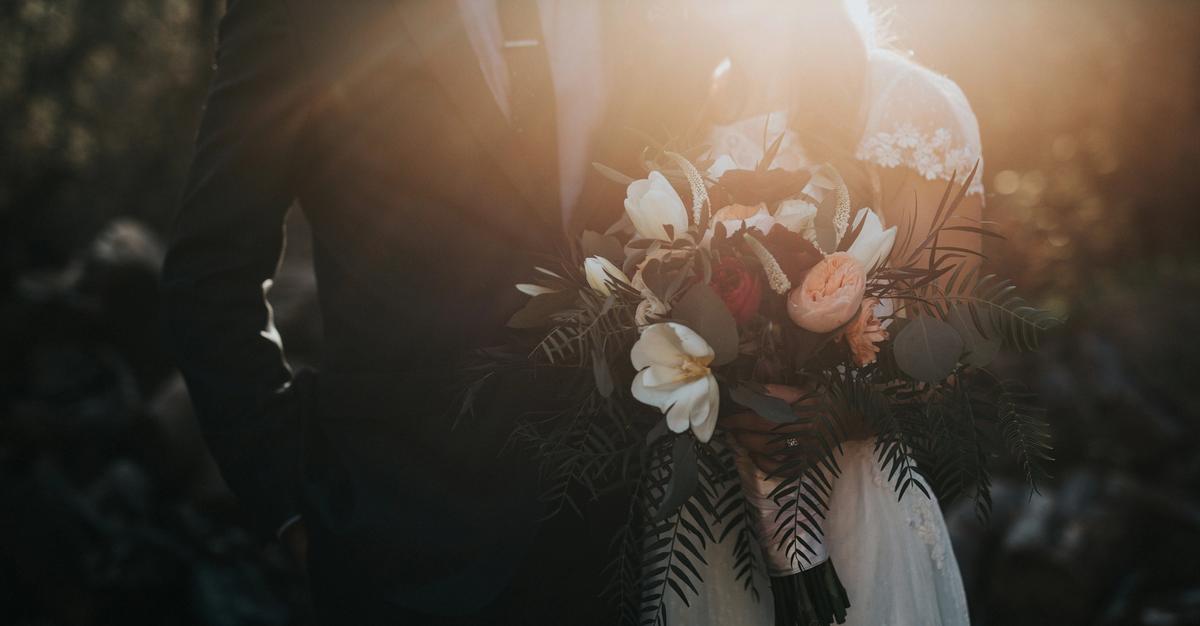 Newly wed couple with wife holding flowers.