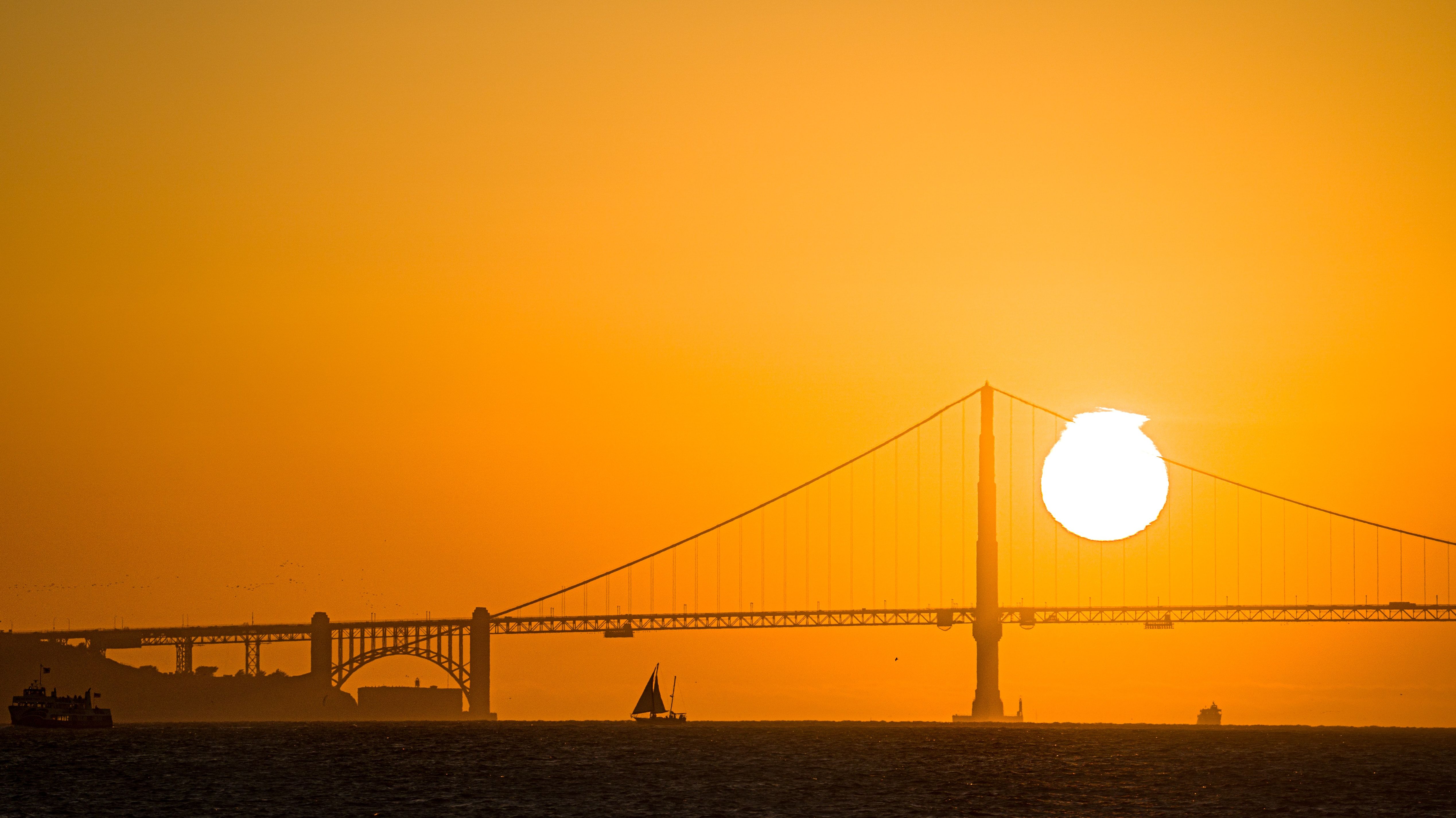 View of an orange sunset near a bridge.