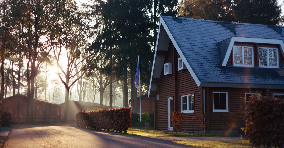 Red house with a blue roof situated in the woods.