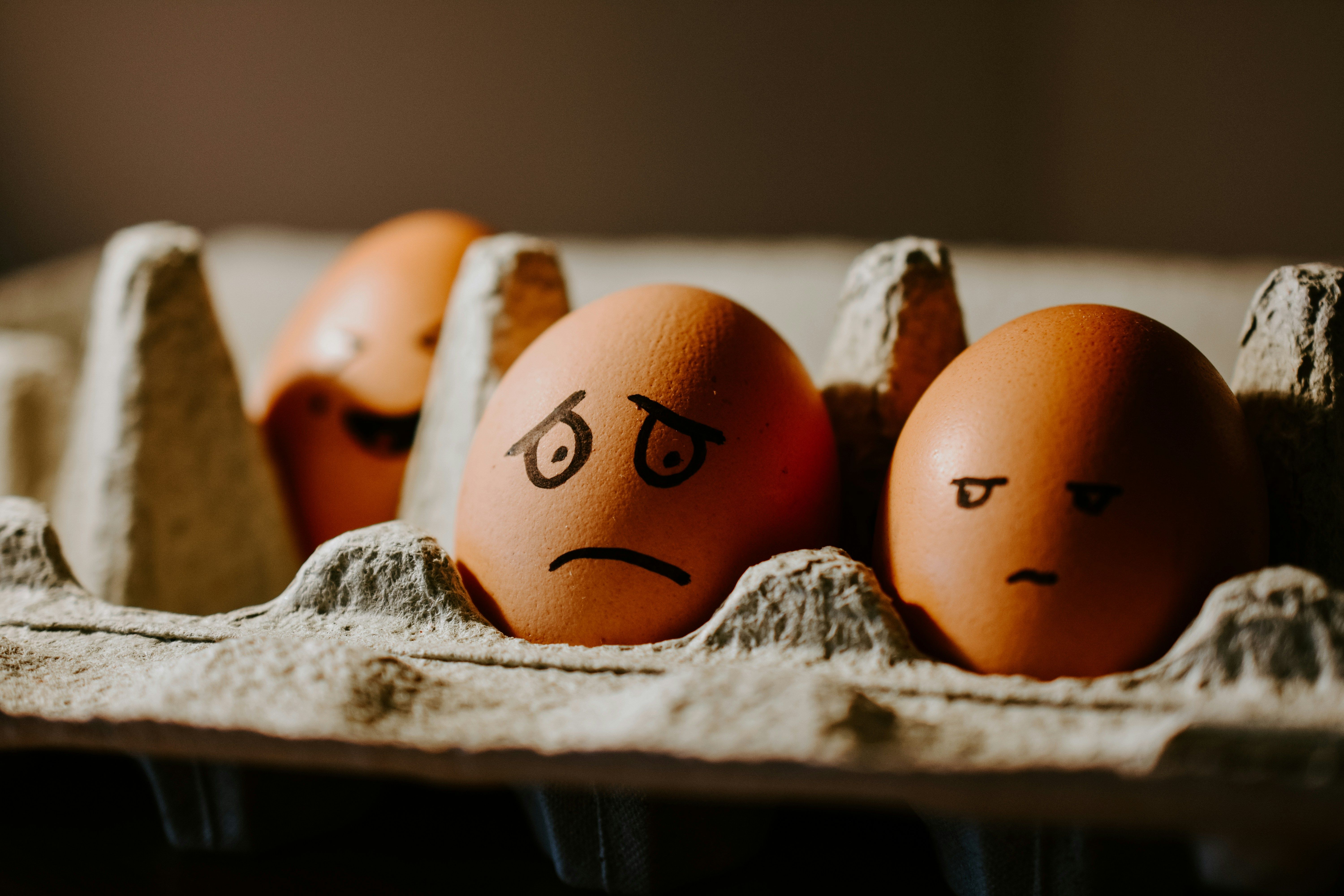 Carton of eggs with frowning faces drown onto eggs.