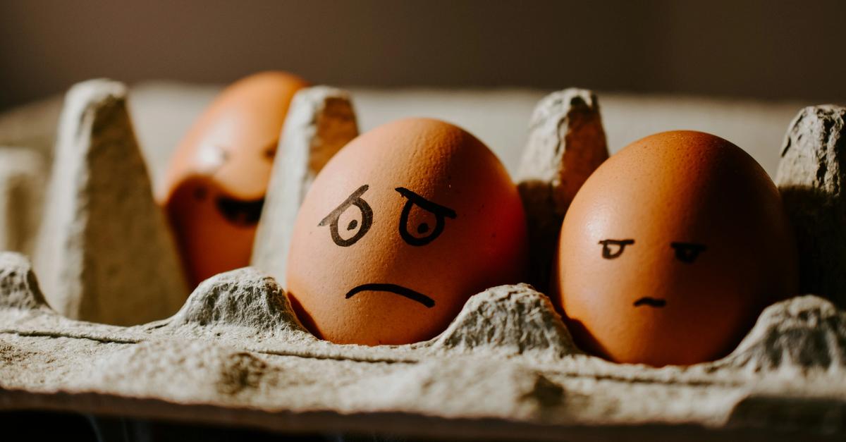 Carton of eggs with frowning faces drown onto eggs.