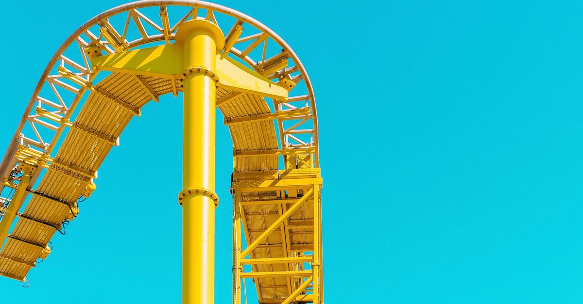Yellow roller coaster ride with blue sky back drop.