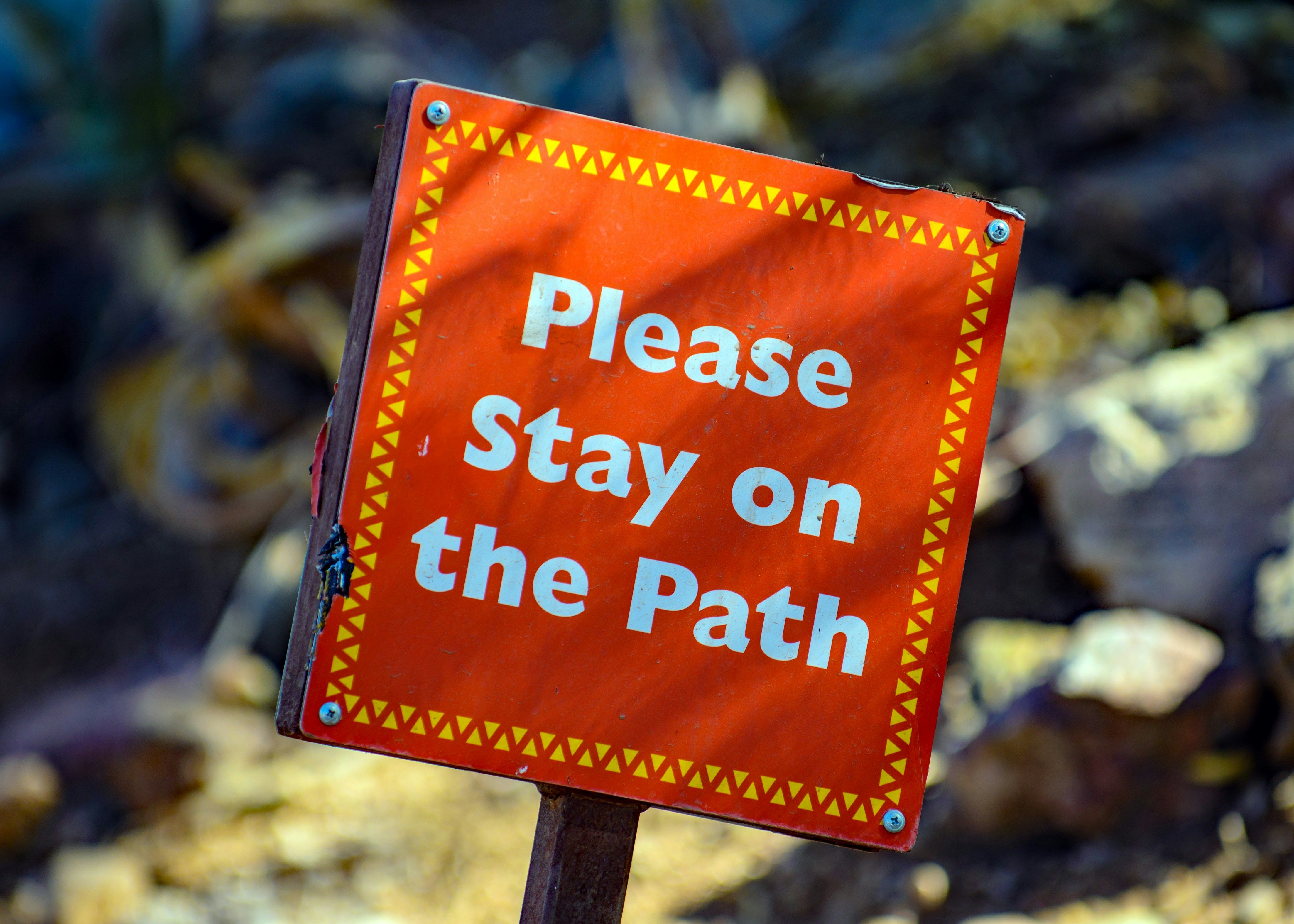 Red sign that reads "Please Stay on the Path".