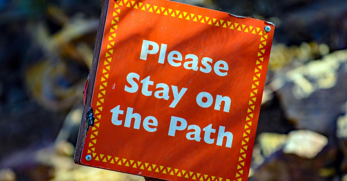 Red sign that reads "Please Stay on the Path".