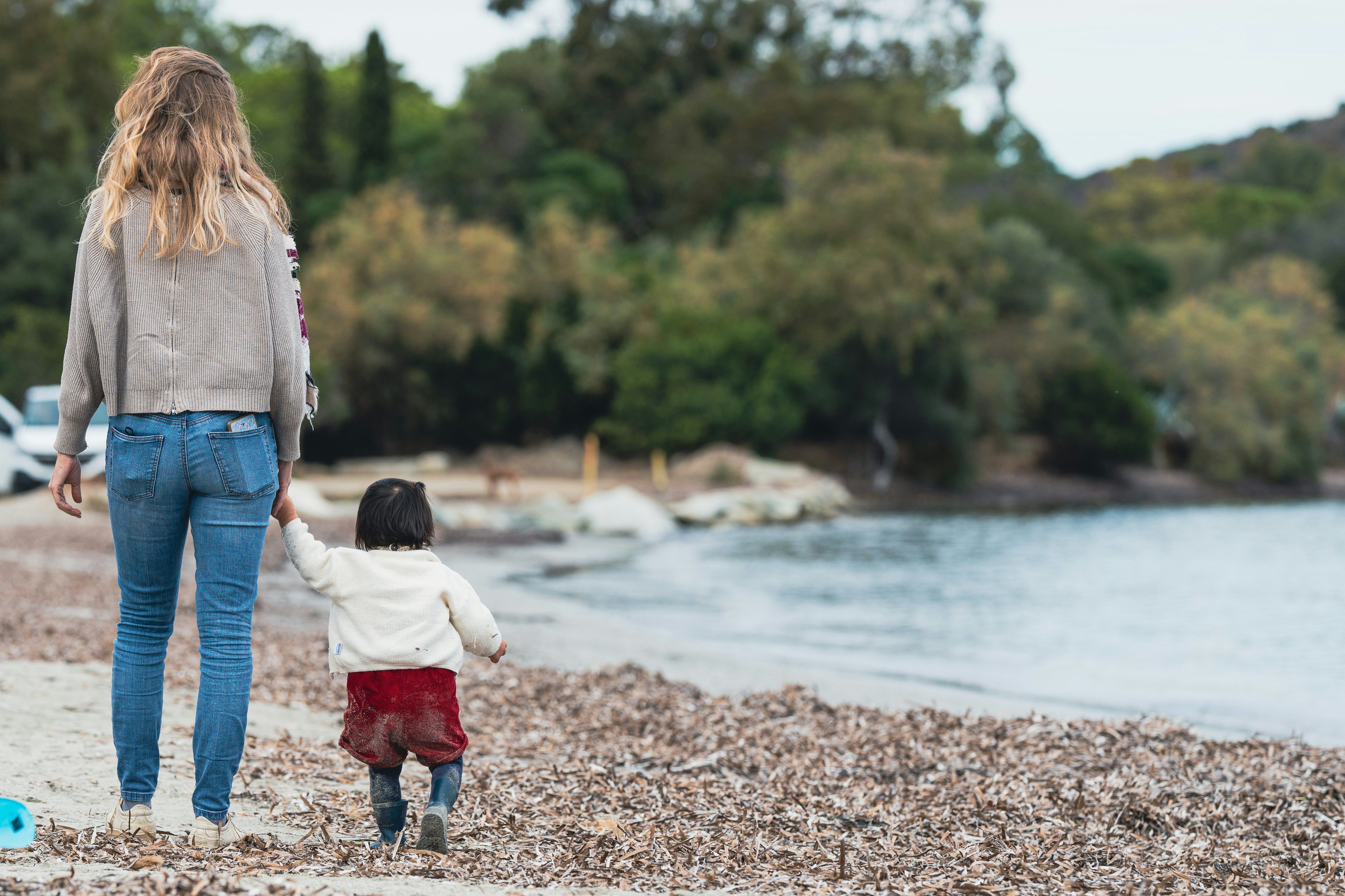Mother and child walking on the beach by guillaume de germaine.