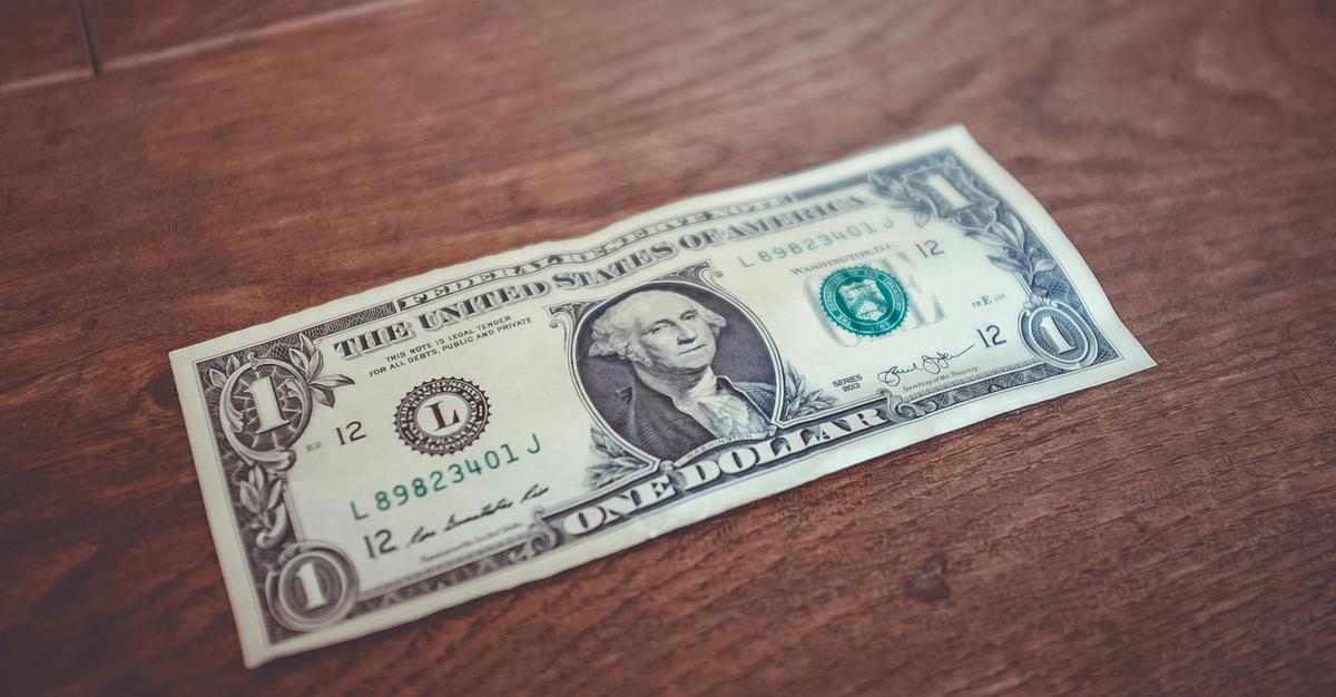 One dollar bill on a wooden table.