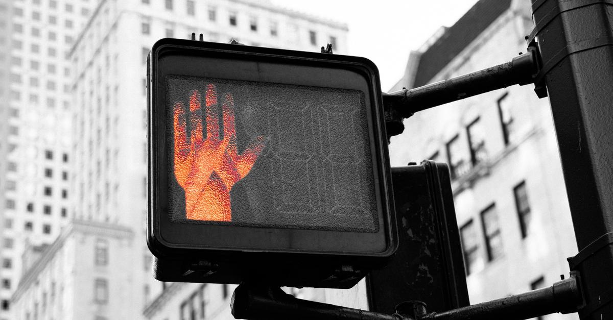 Pedestrian traffic light with a red hand for stop.