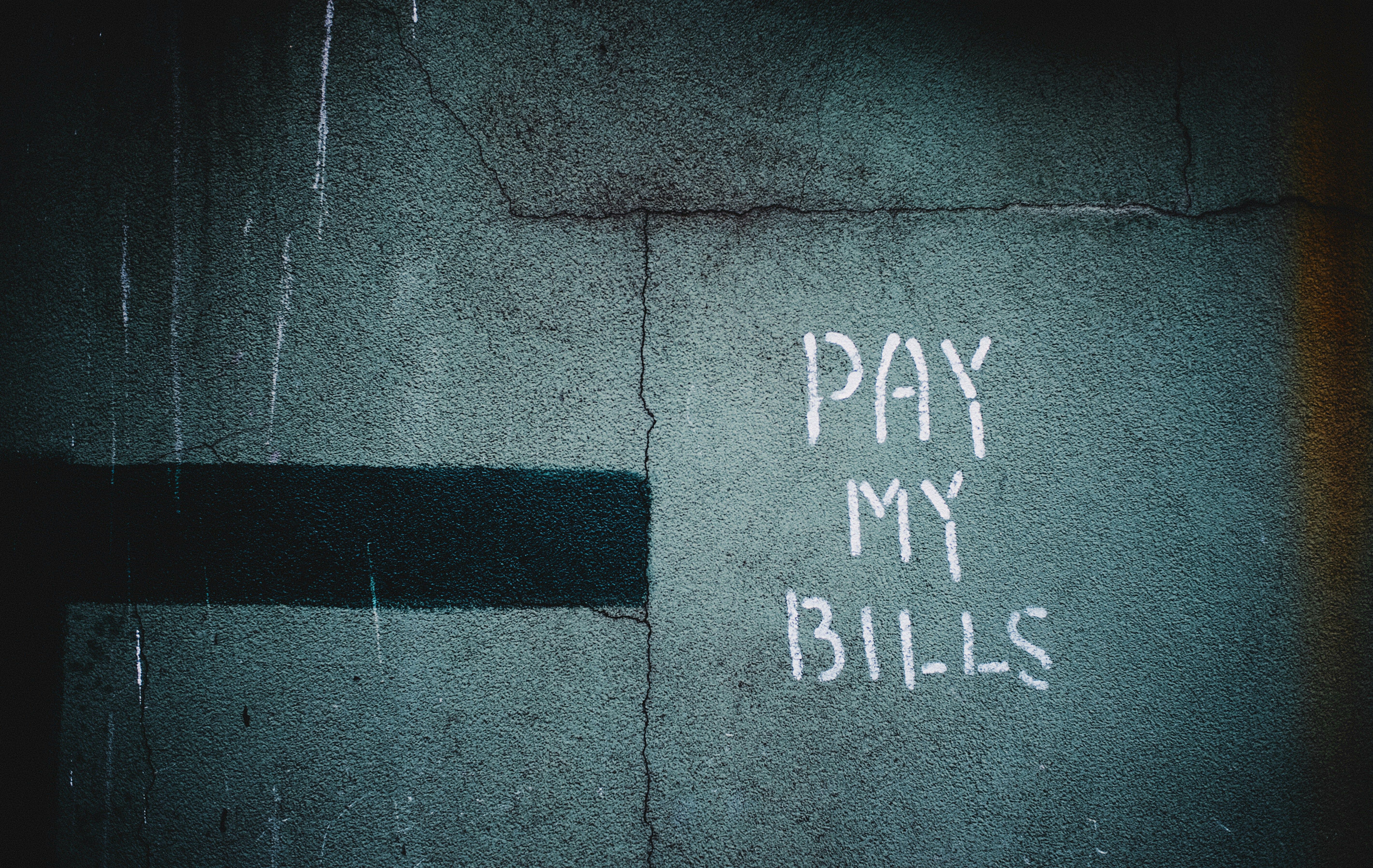 A concrete wall with "Pay My Bills" posted on it by Hiroshi Kimura.