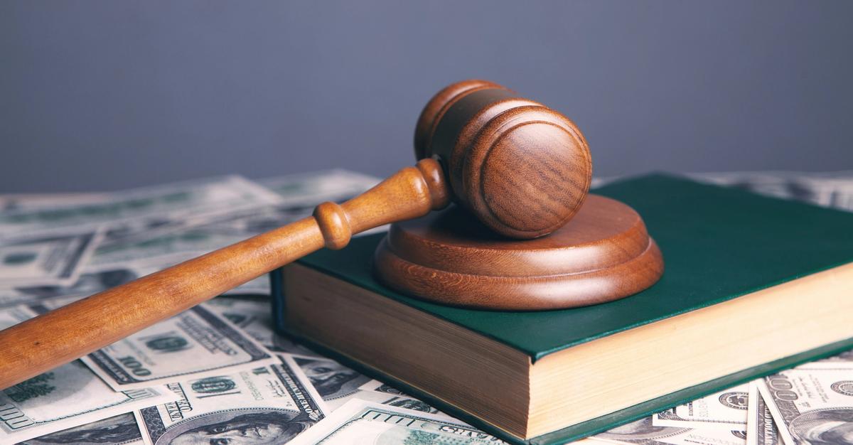 Gavel and law book sitting on top of money by Susan Bughdaryan.