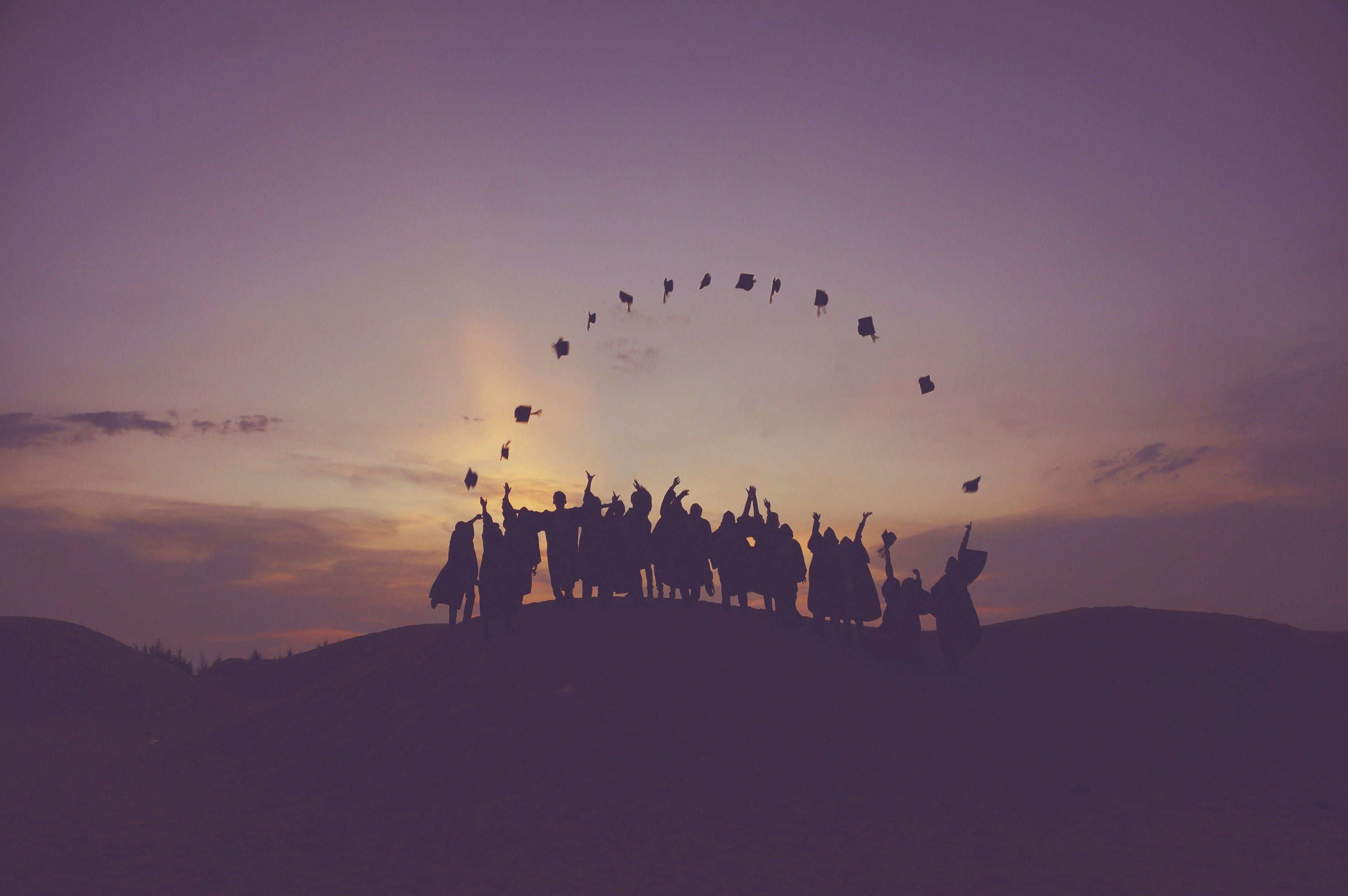 Graduates throwing their caps in the sunset.