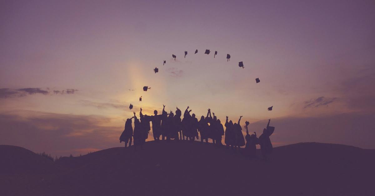 Graduates throwing their caps in the sunset.