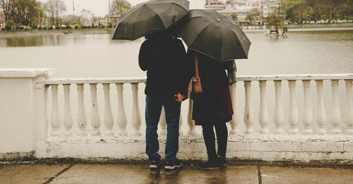 Couple holding hands by a lake.