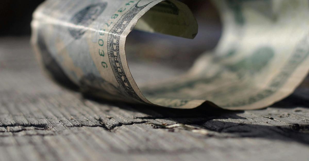 Rolled up twenty dollar bill on the cracked pavement by Joshua Hoehne.