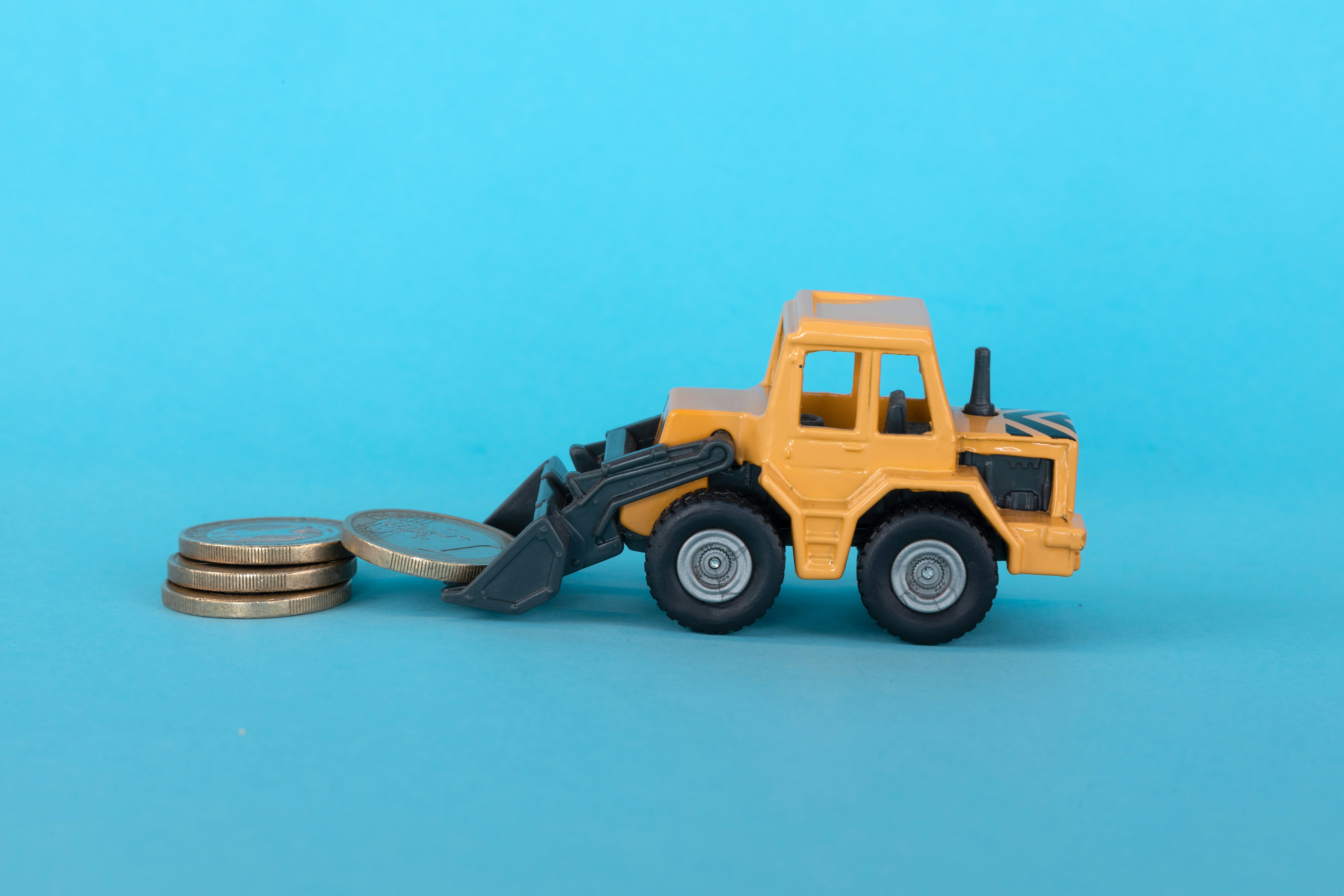 A toy excavation truck picking up money.