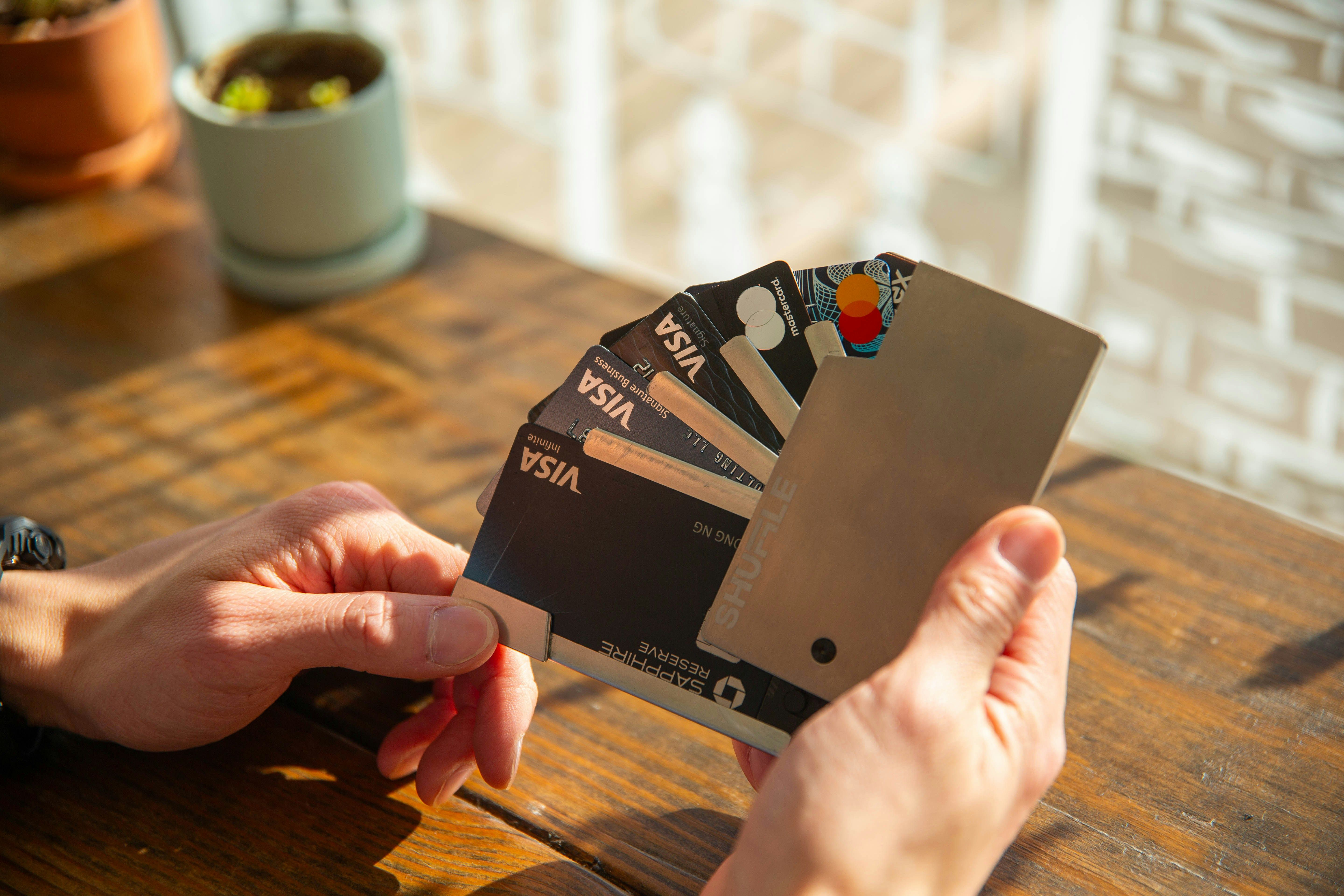 Image of person holding up multiple credit cards (Visa and Mastercard), by Jim Chen.