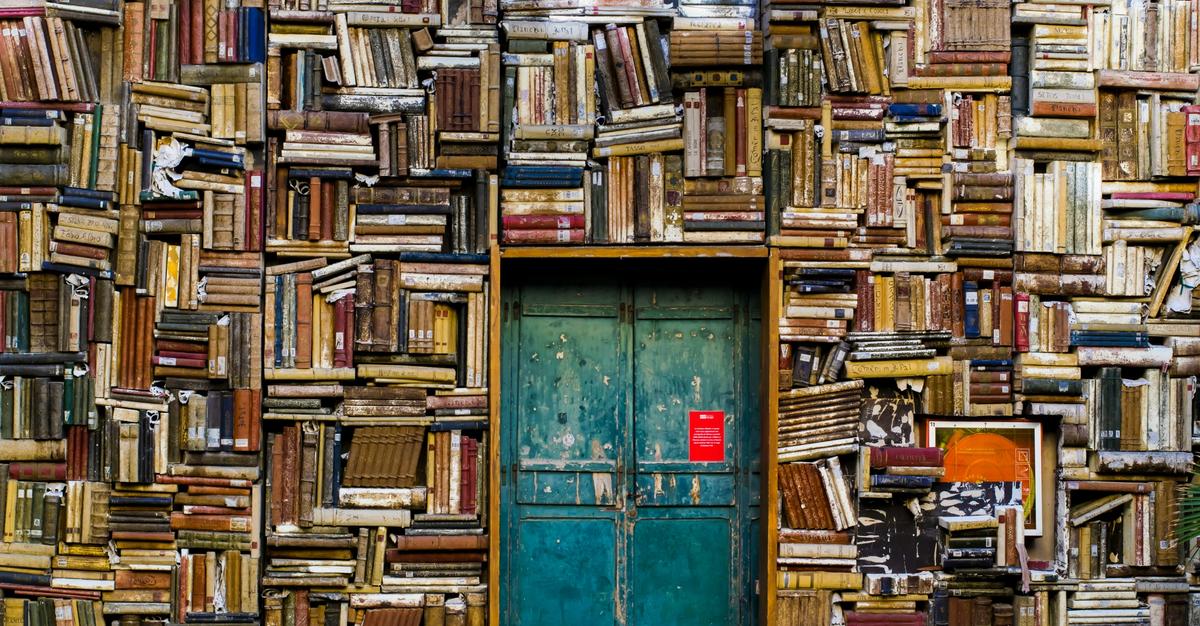 Teal door surrounded by books sloppily placed all around the wall.
