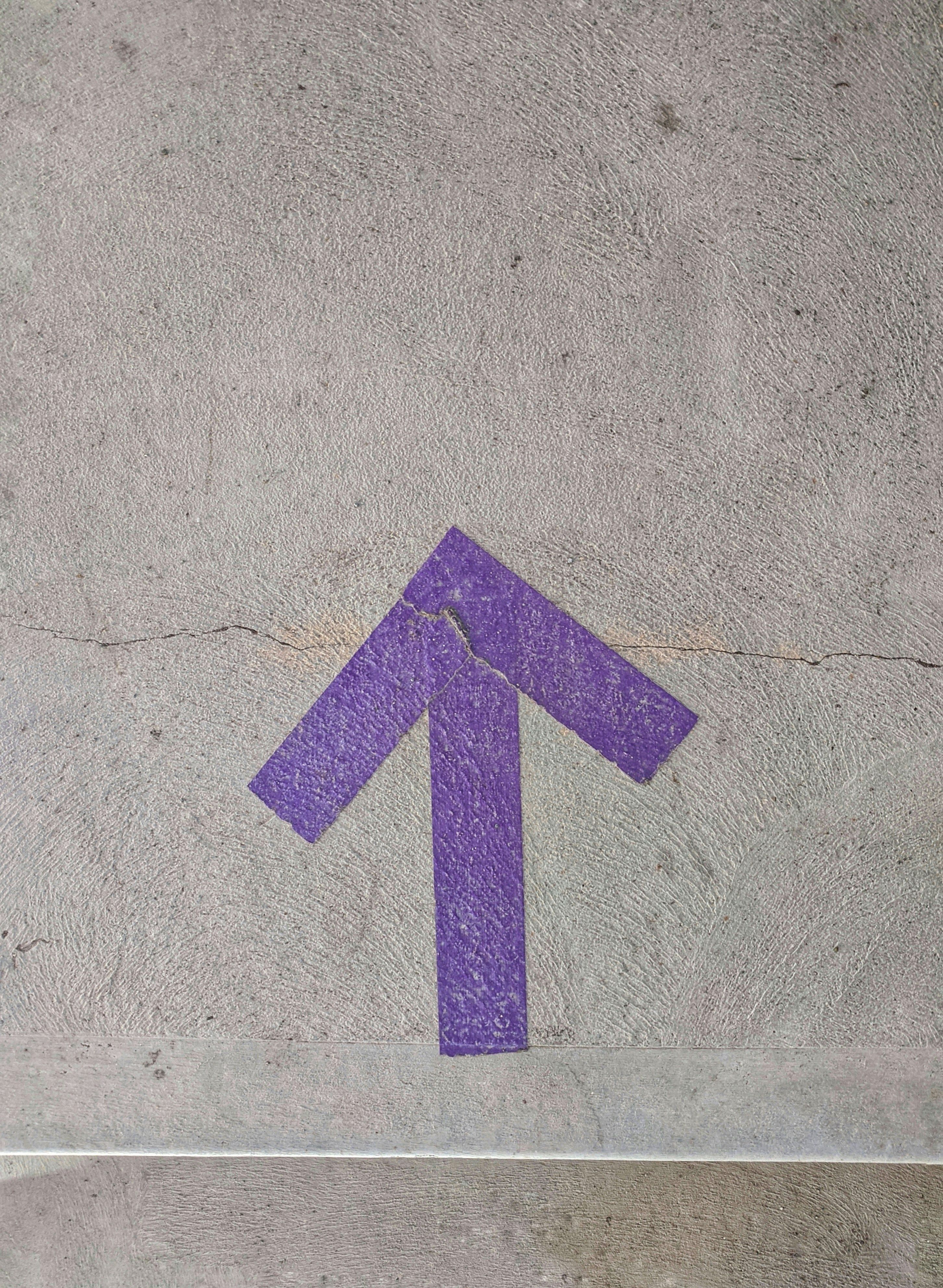 Purple arrow pointing up painted onto concrete.