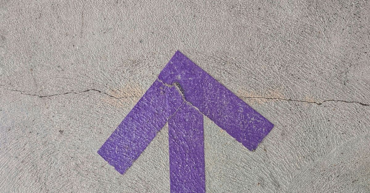 Purple arrow pointing up painted onto concrete.
