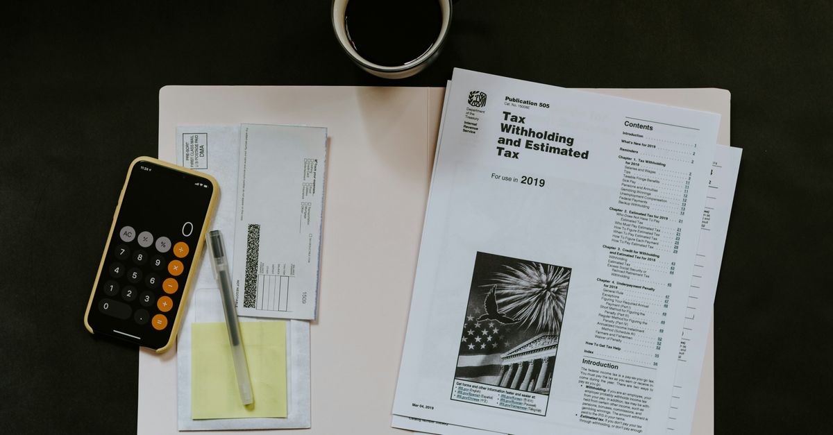 Paperwork on desk with an iphone calculator and a cup of coffee.