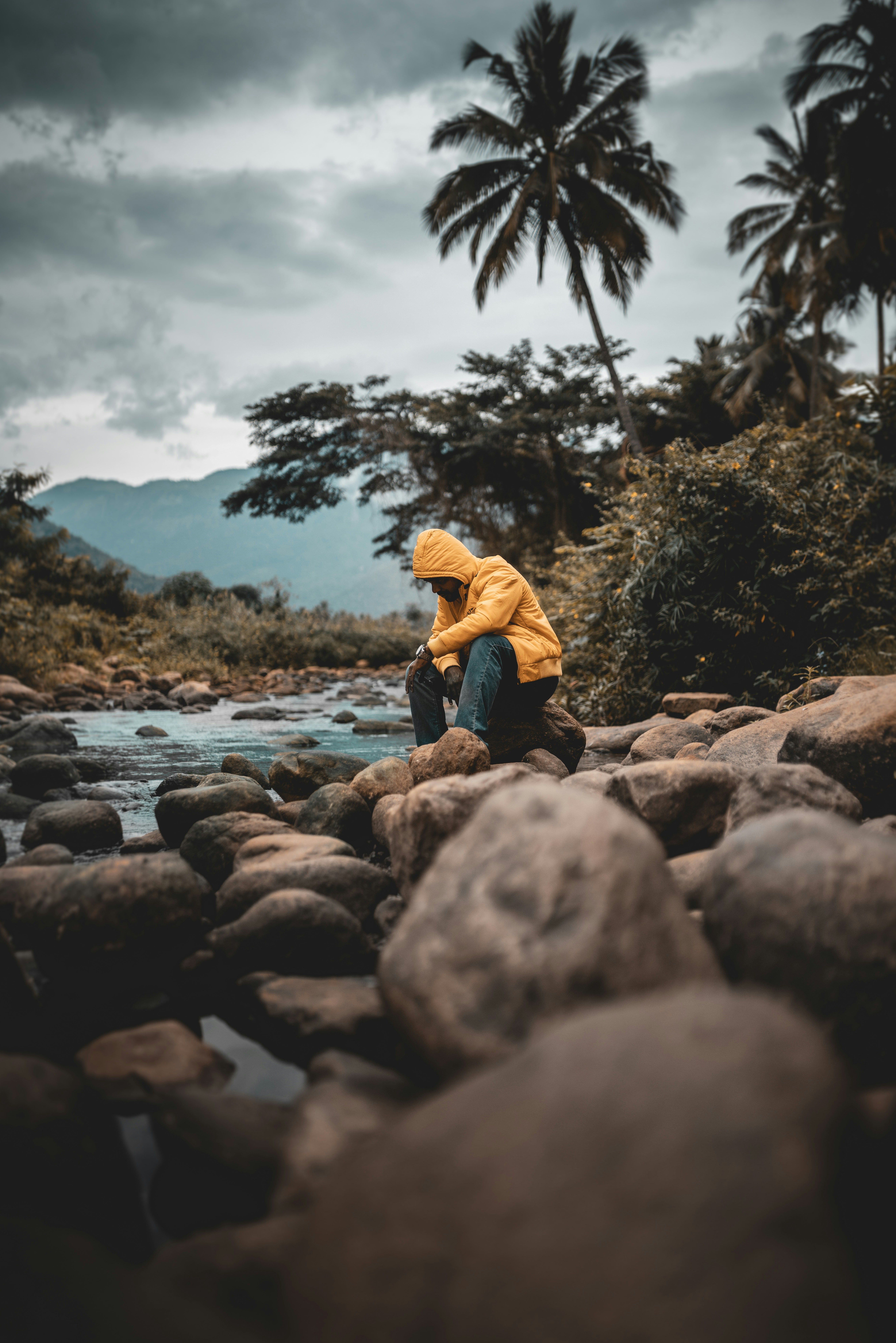 Man looking down at a river creek with rocks.