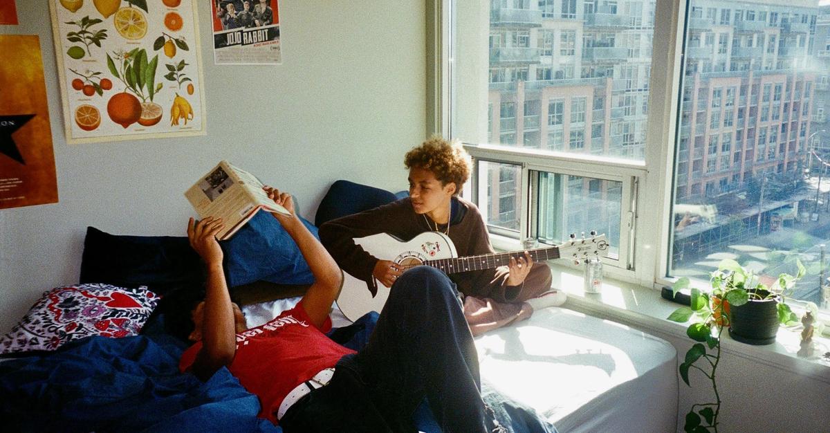 Two roomates relaxing by a window by Anita Monteiro.