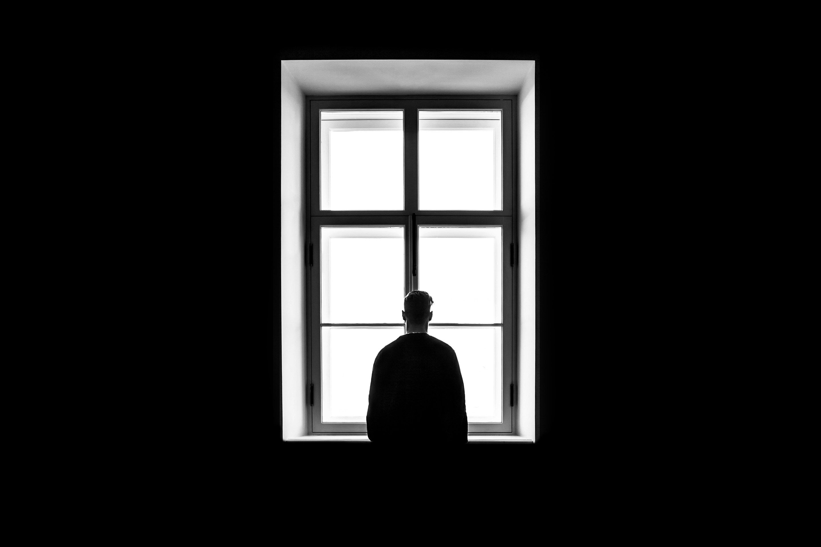 Man peering through window in darkness.