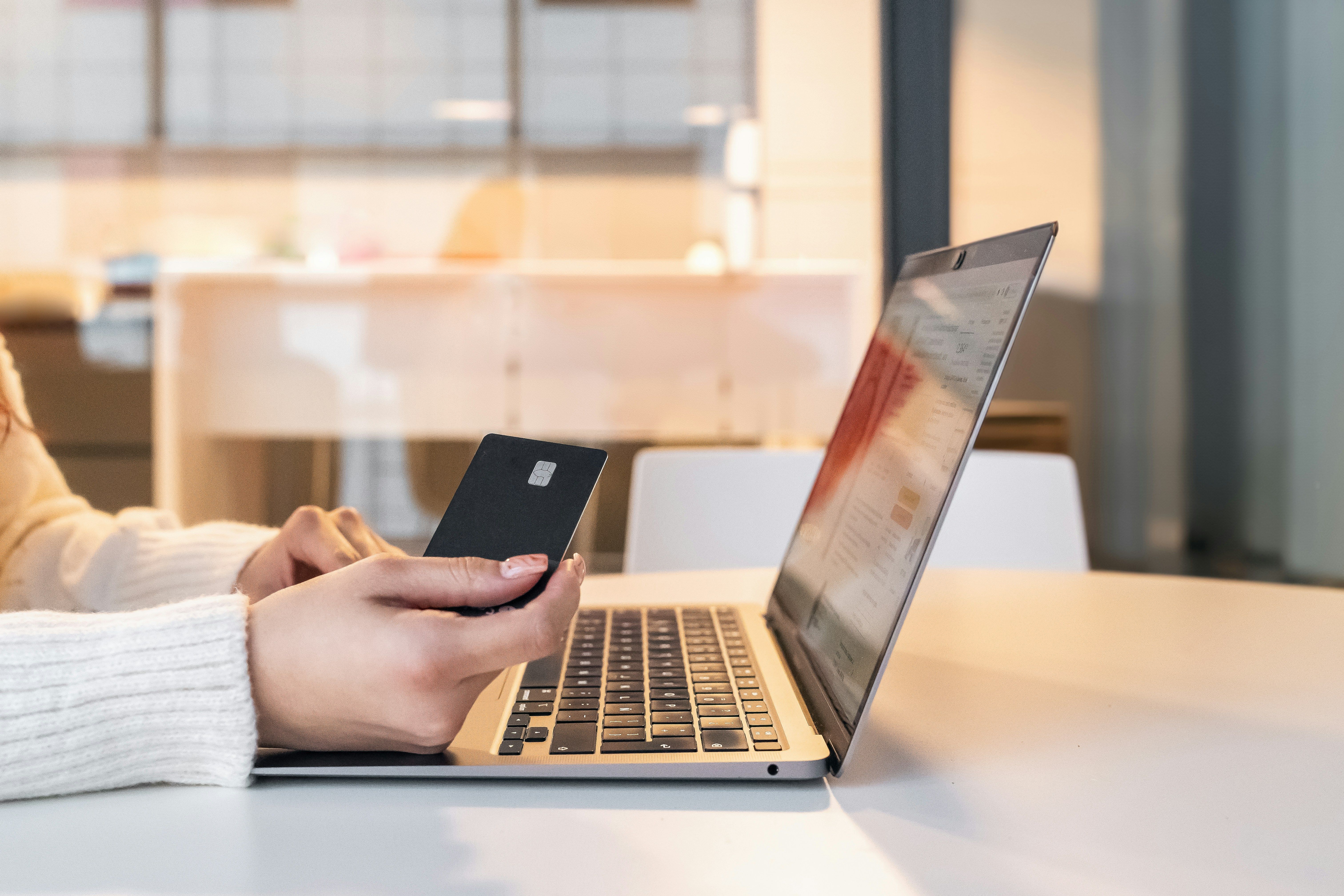 Women purchasing with/using a credit card on a laptop.
