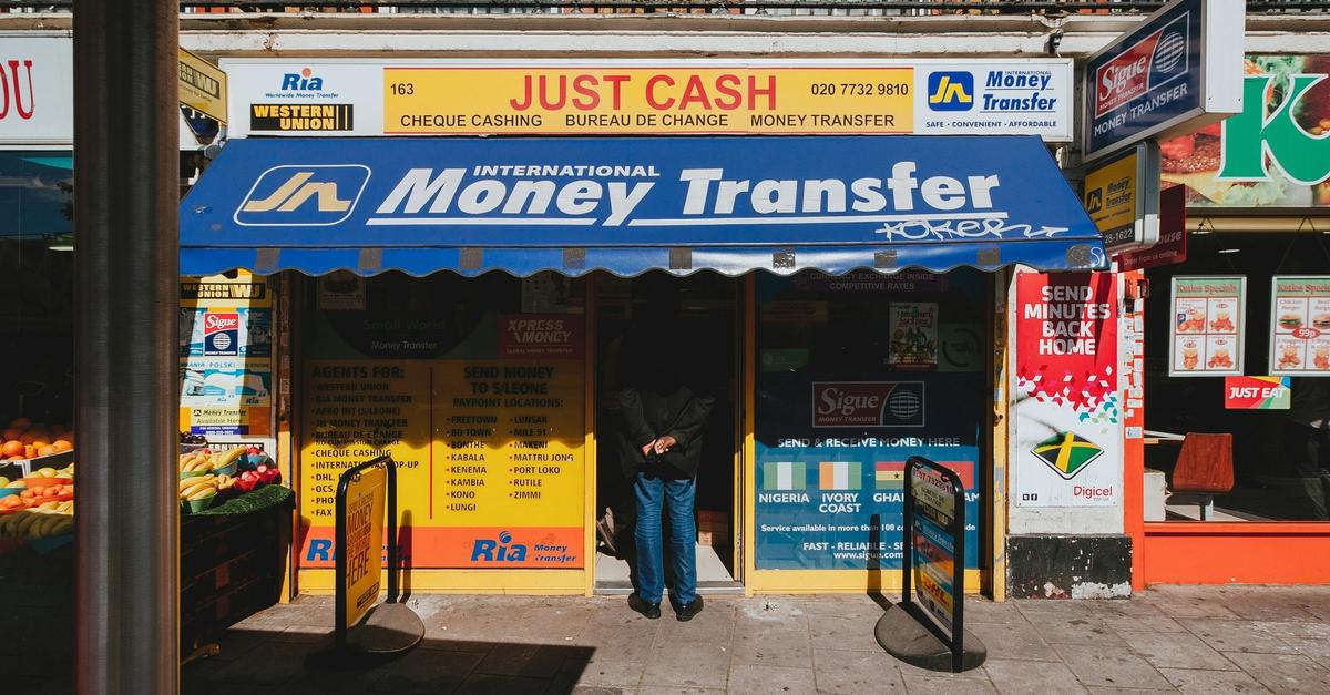 Storefront with sign saying Just Cash International Money Transfer by Alistair Macrobert.
