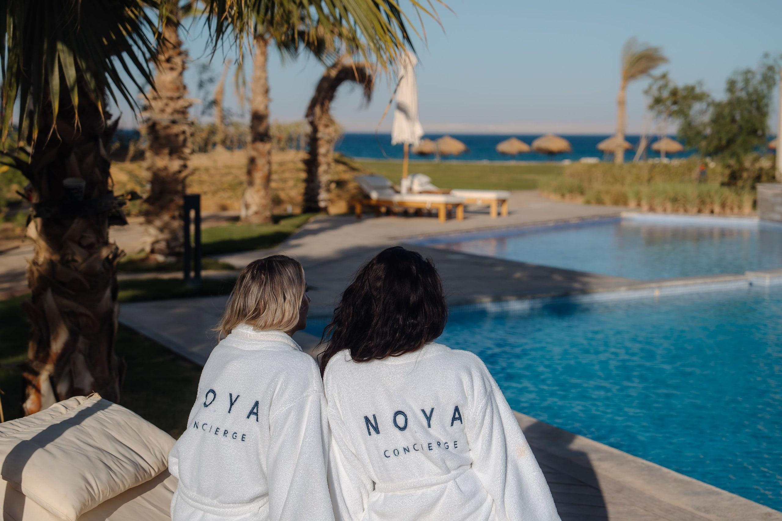 Two guests in NOYA robes looking out over a pool