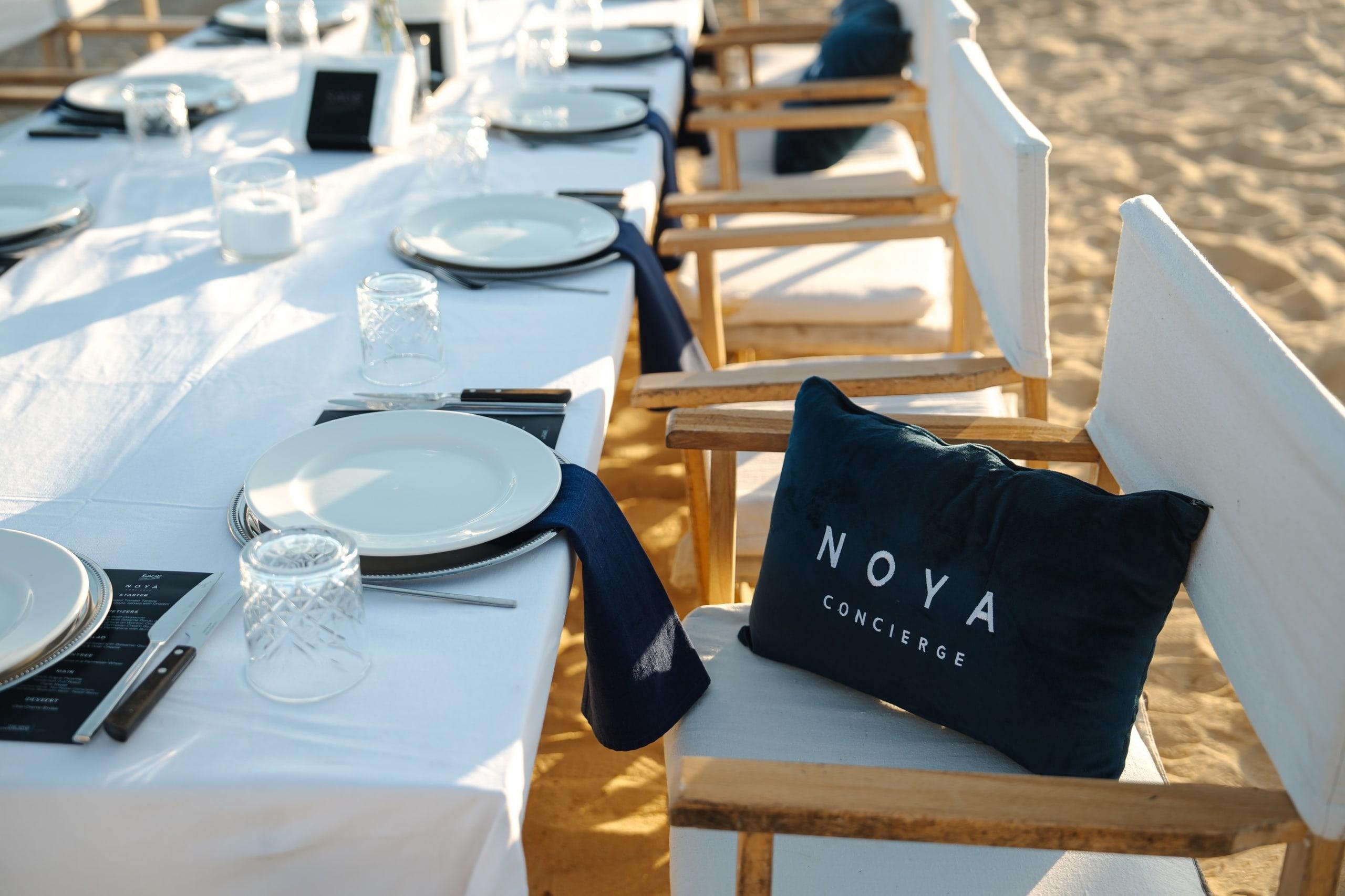 A dinner table on the sand with NOYA cushions