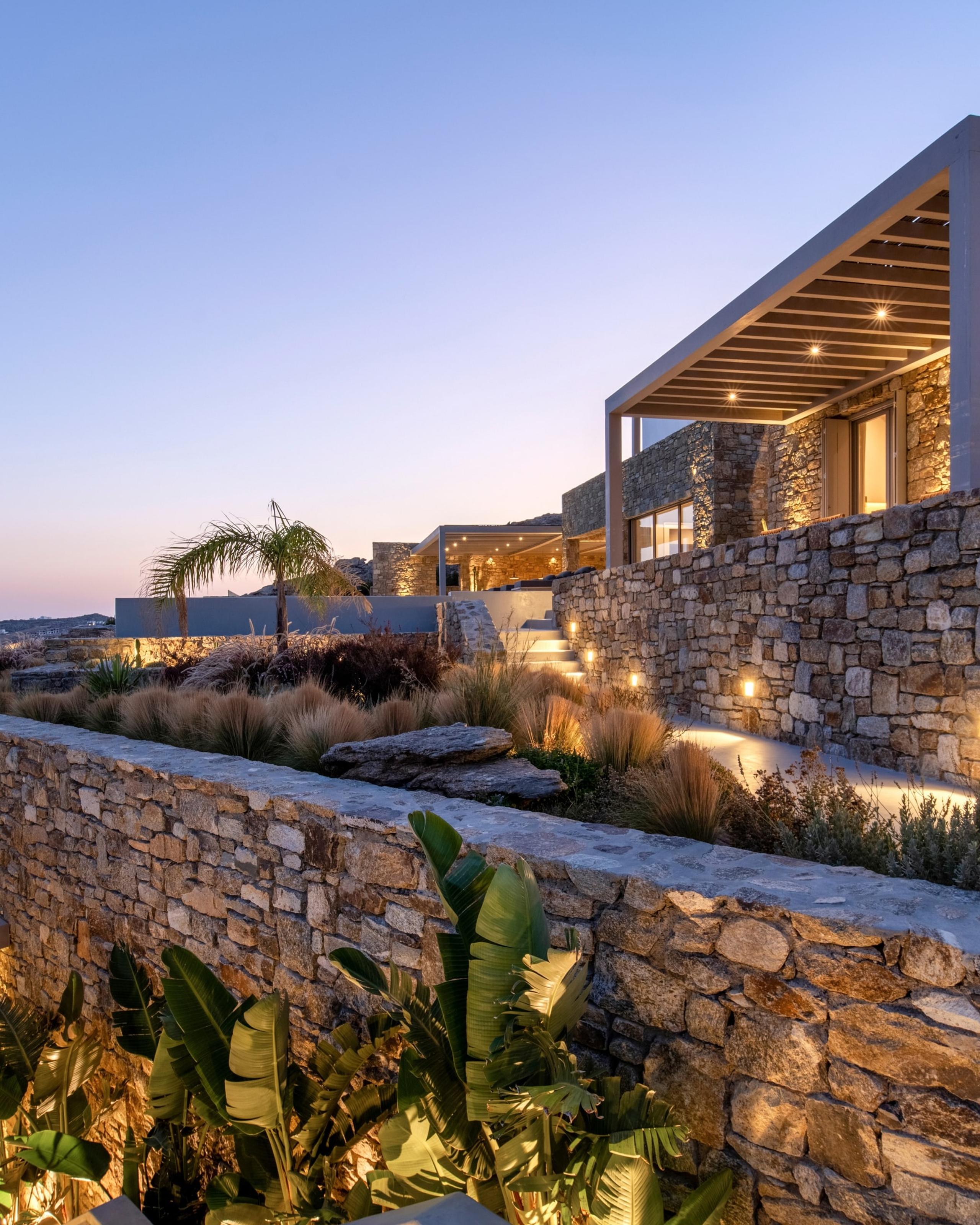 A stone villa and terraced garden lit at dusk in Mykonos
