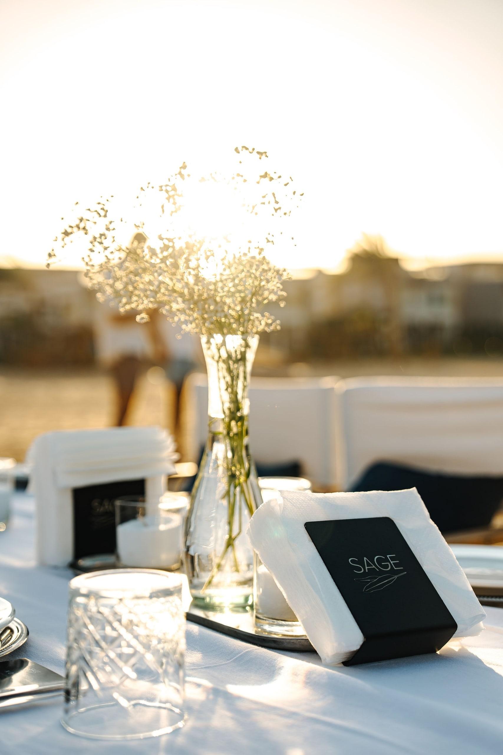 A table set with a menu card and flowers at sunset