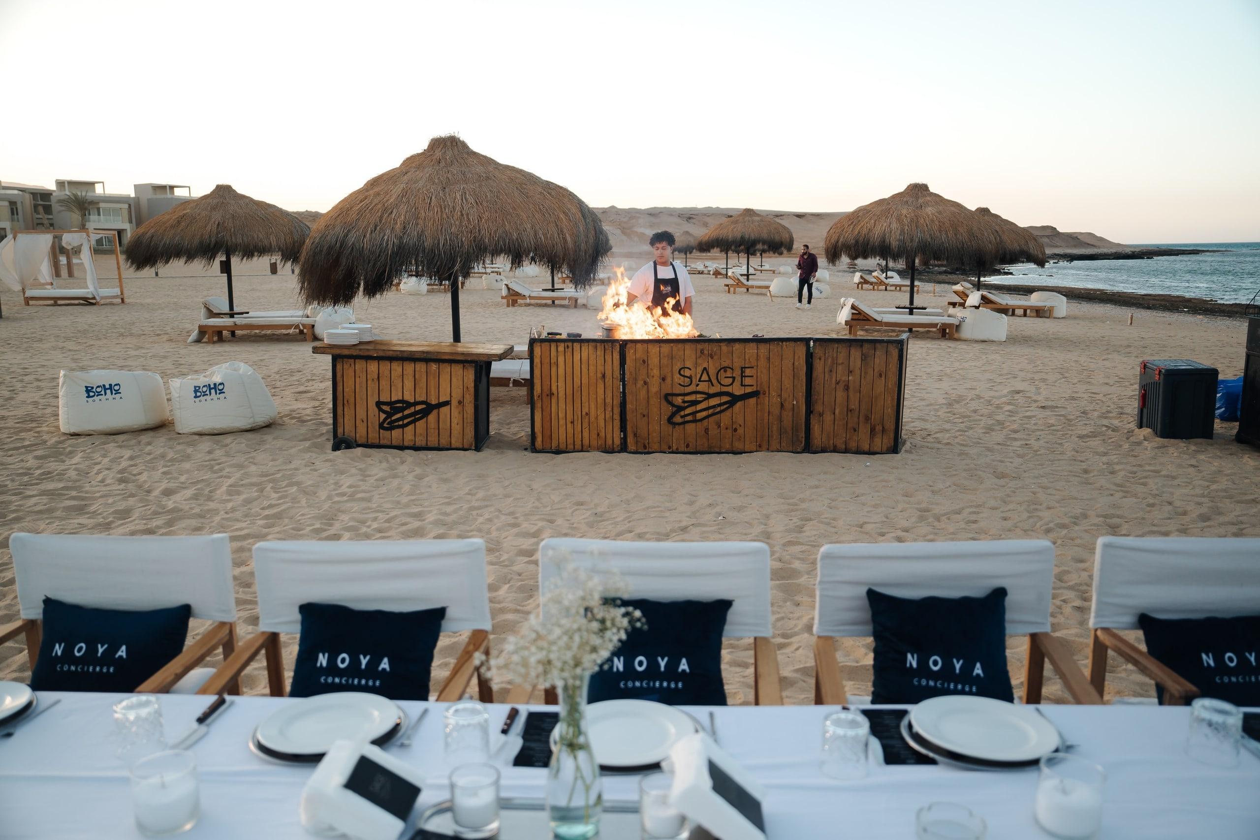 A beach dinner set up with NOYA cushions and a grill station