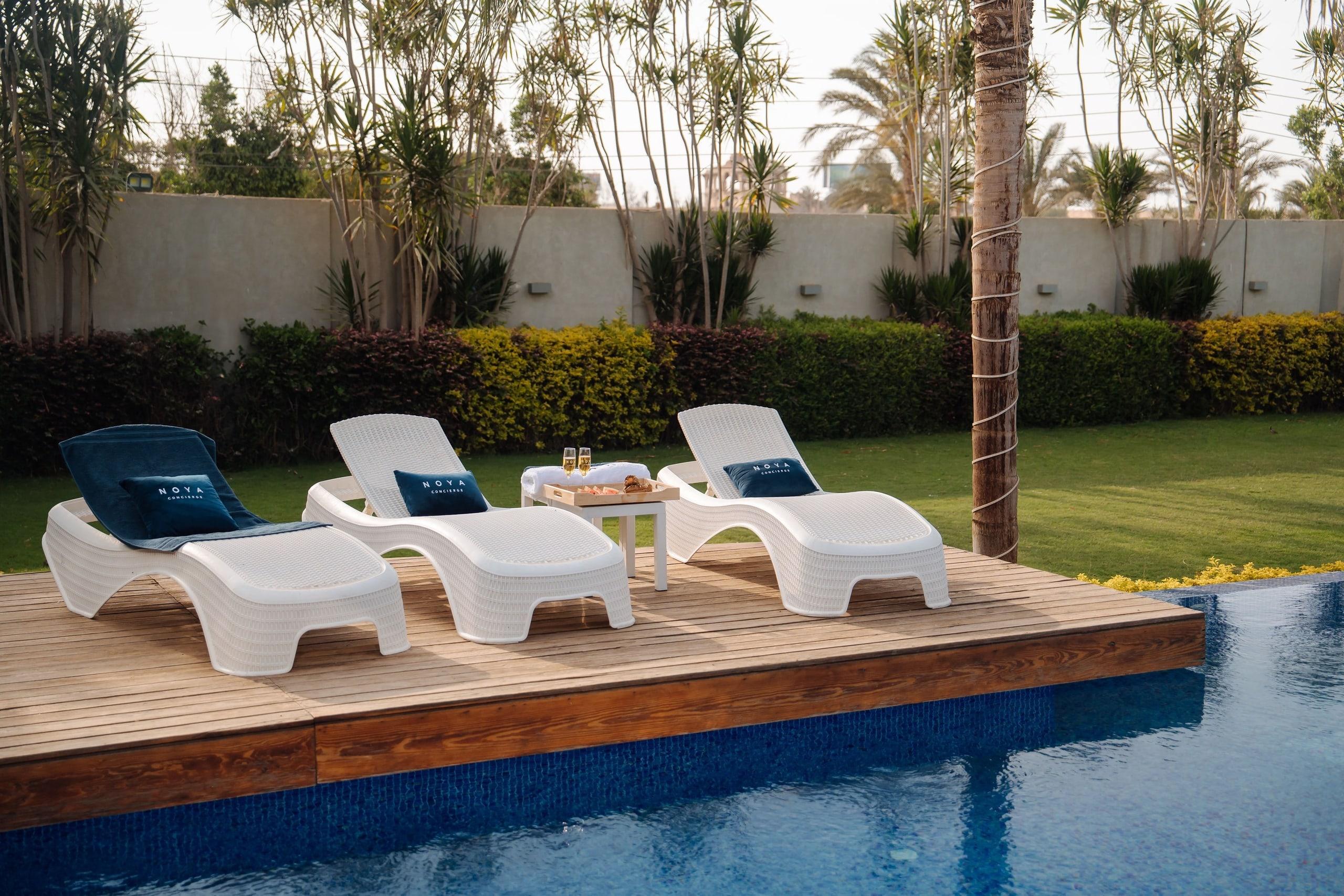 Poolside loungers with NOYA cushions in a garden