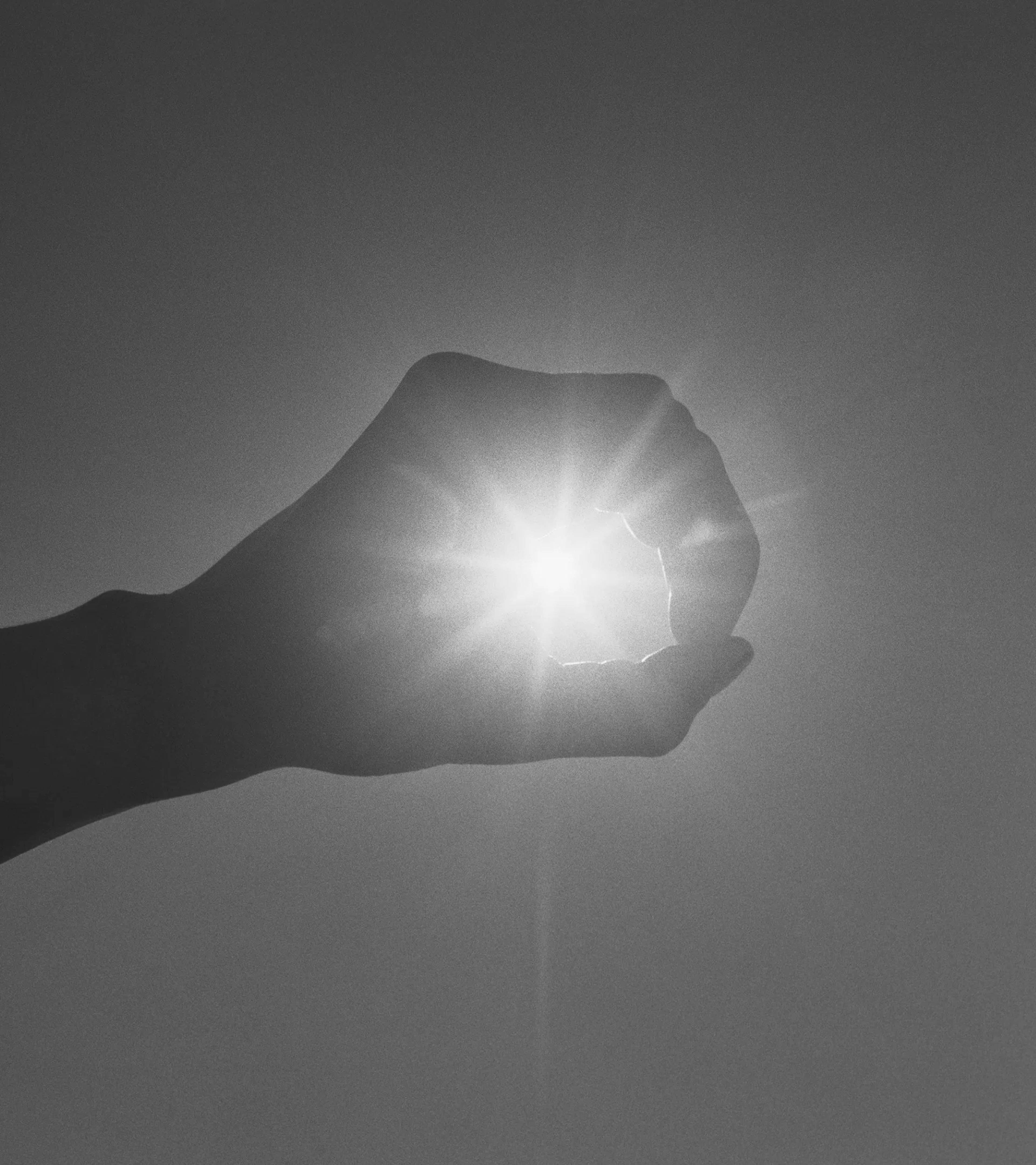 A hand held up to the sun seems to grasp the circle of light in an open fist.