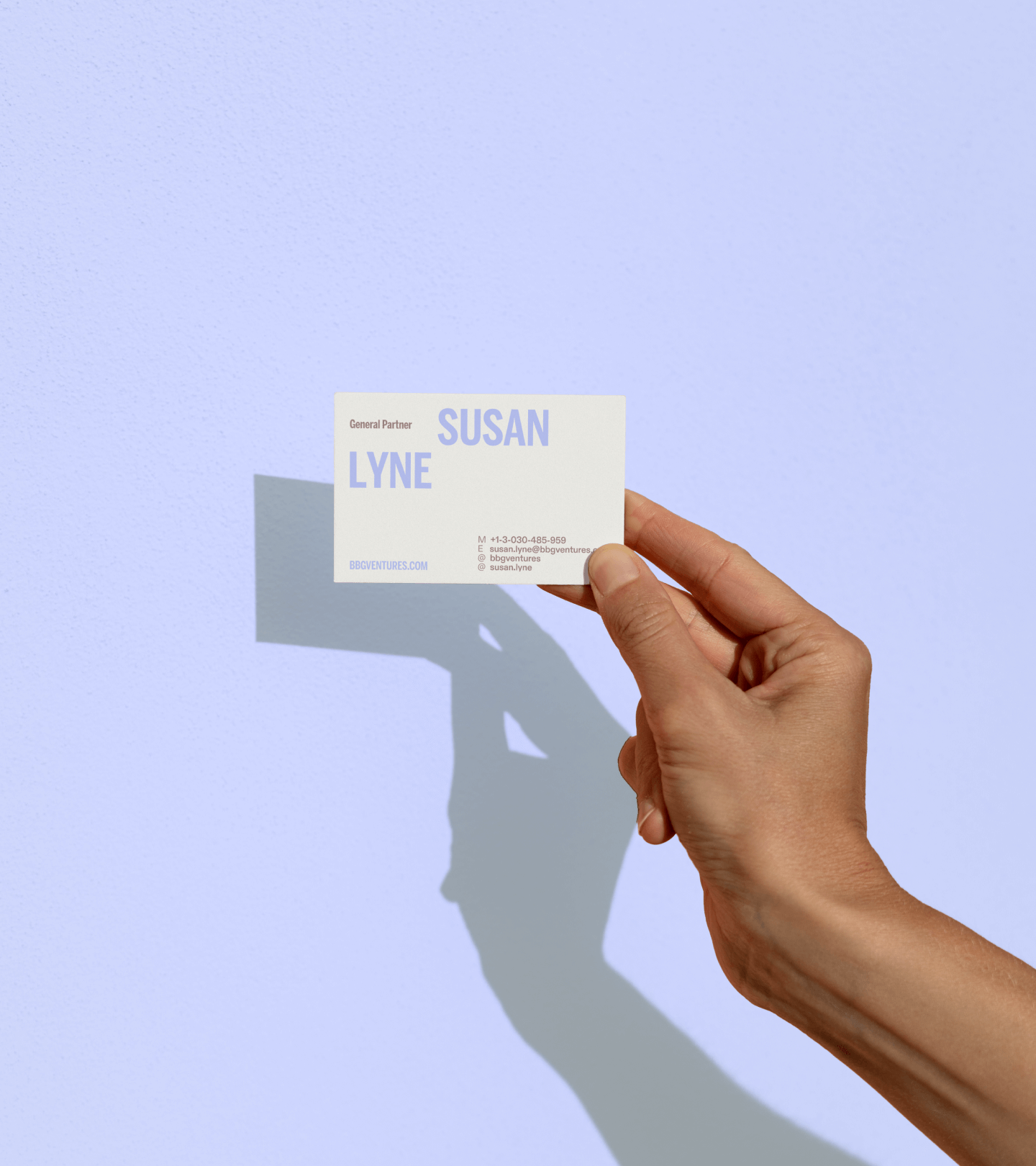 Hand holding business card in front of purple background