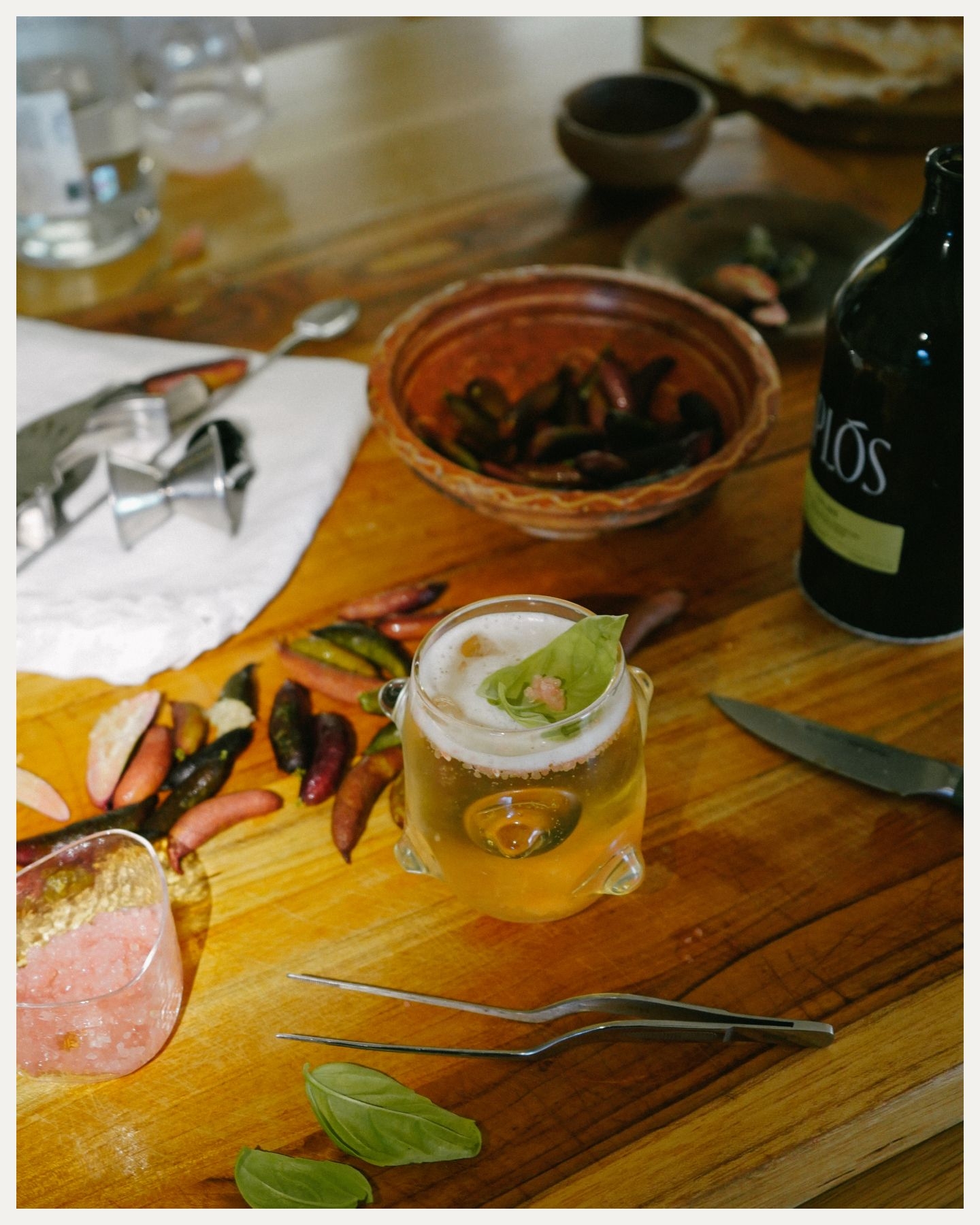 A cocktail surrounded by bartenders tools and ingredients.