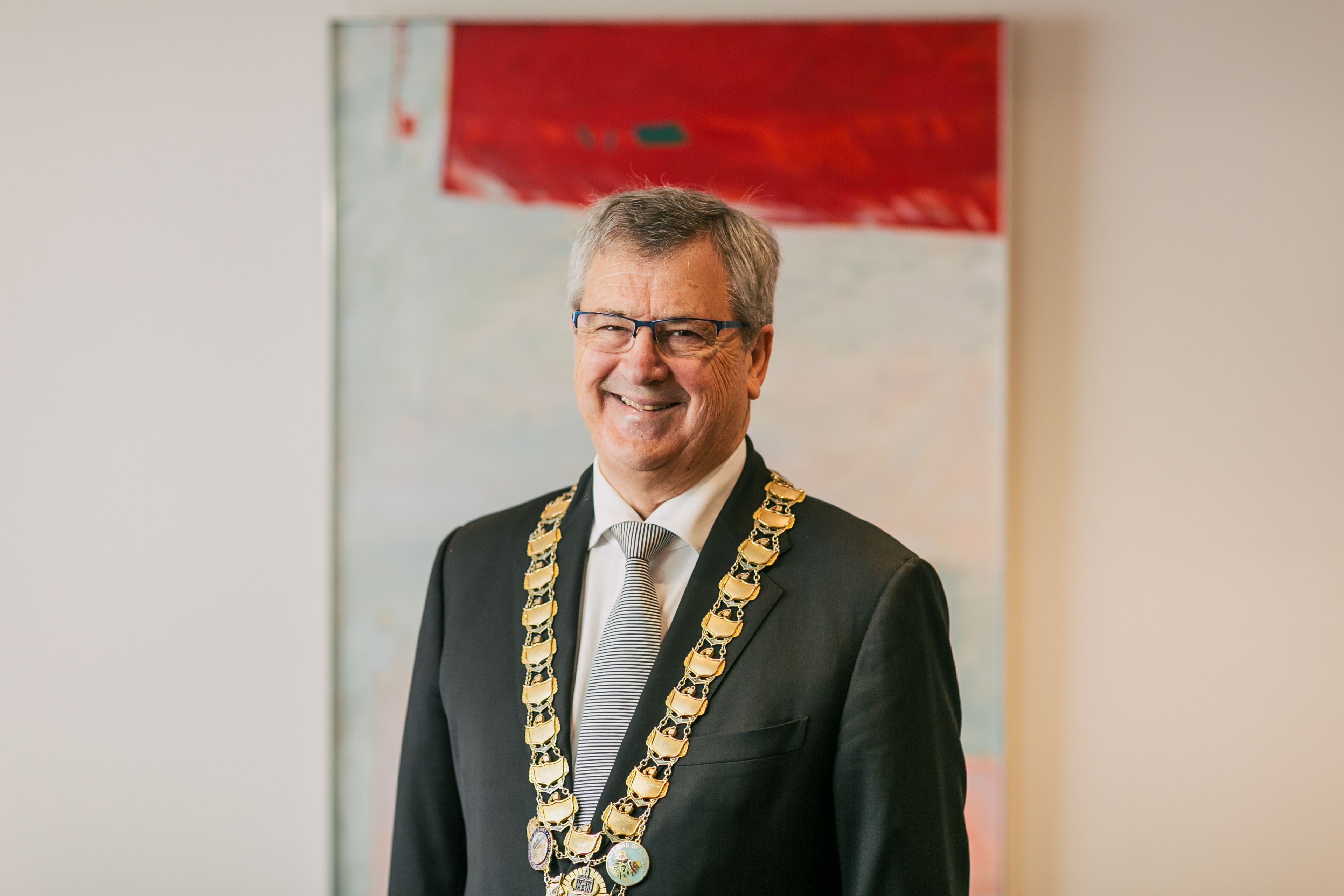 Portrait image of Dennis Wellington wearing a suit and the Mayoral chains