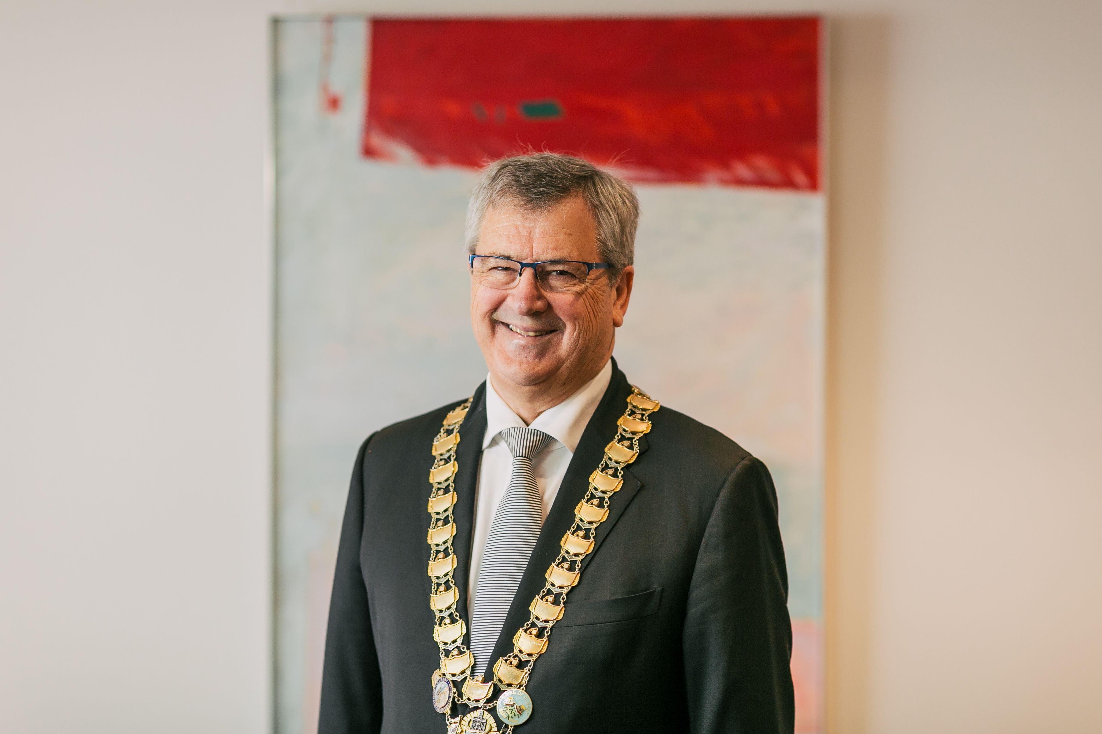 Portrait image of Dennis Wellington wearing a suit and the Mayoral chains