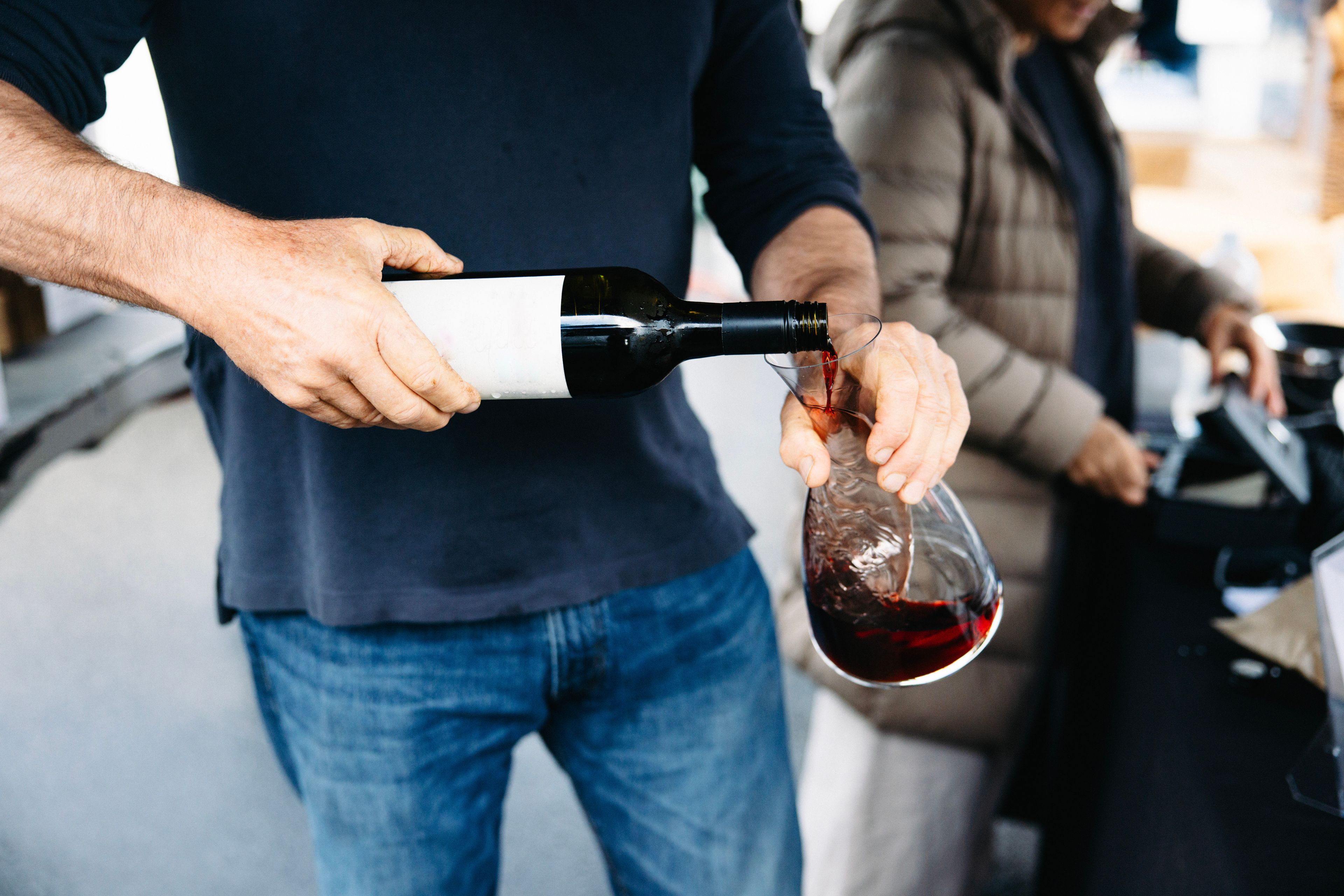 A bottle of red wine being poured into a carafe
