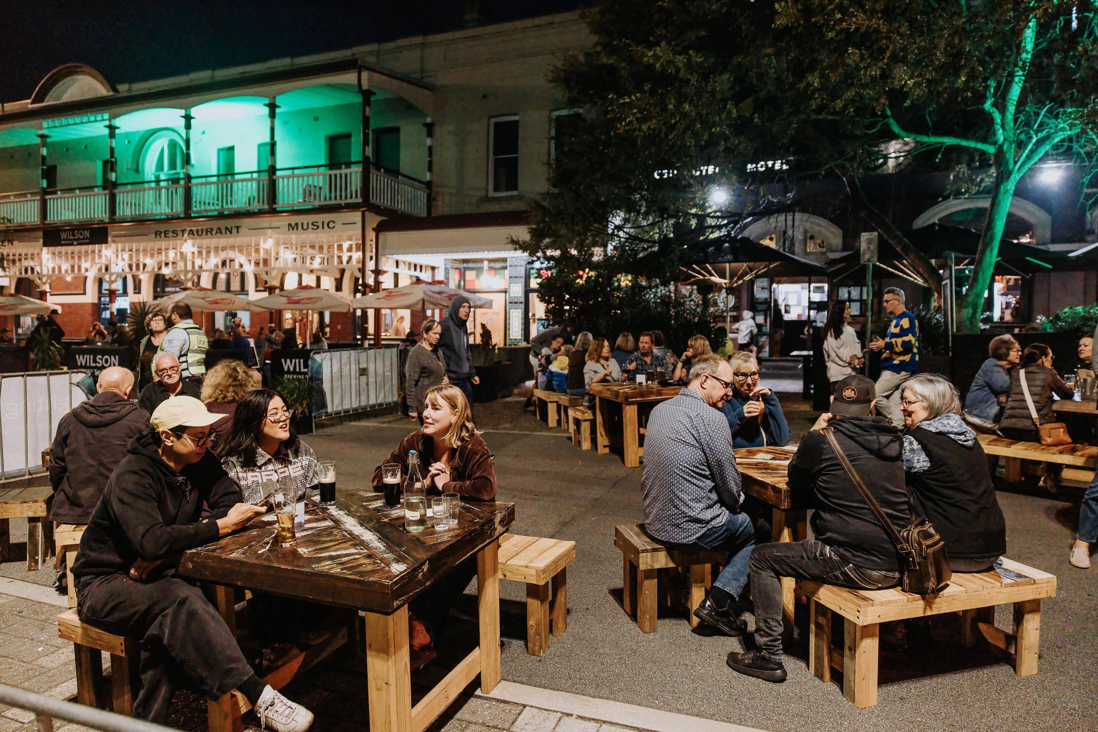 People enjoying al fresco seating at night outside a lively looking pub
