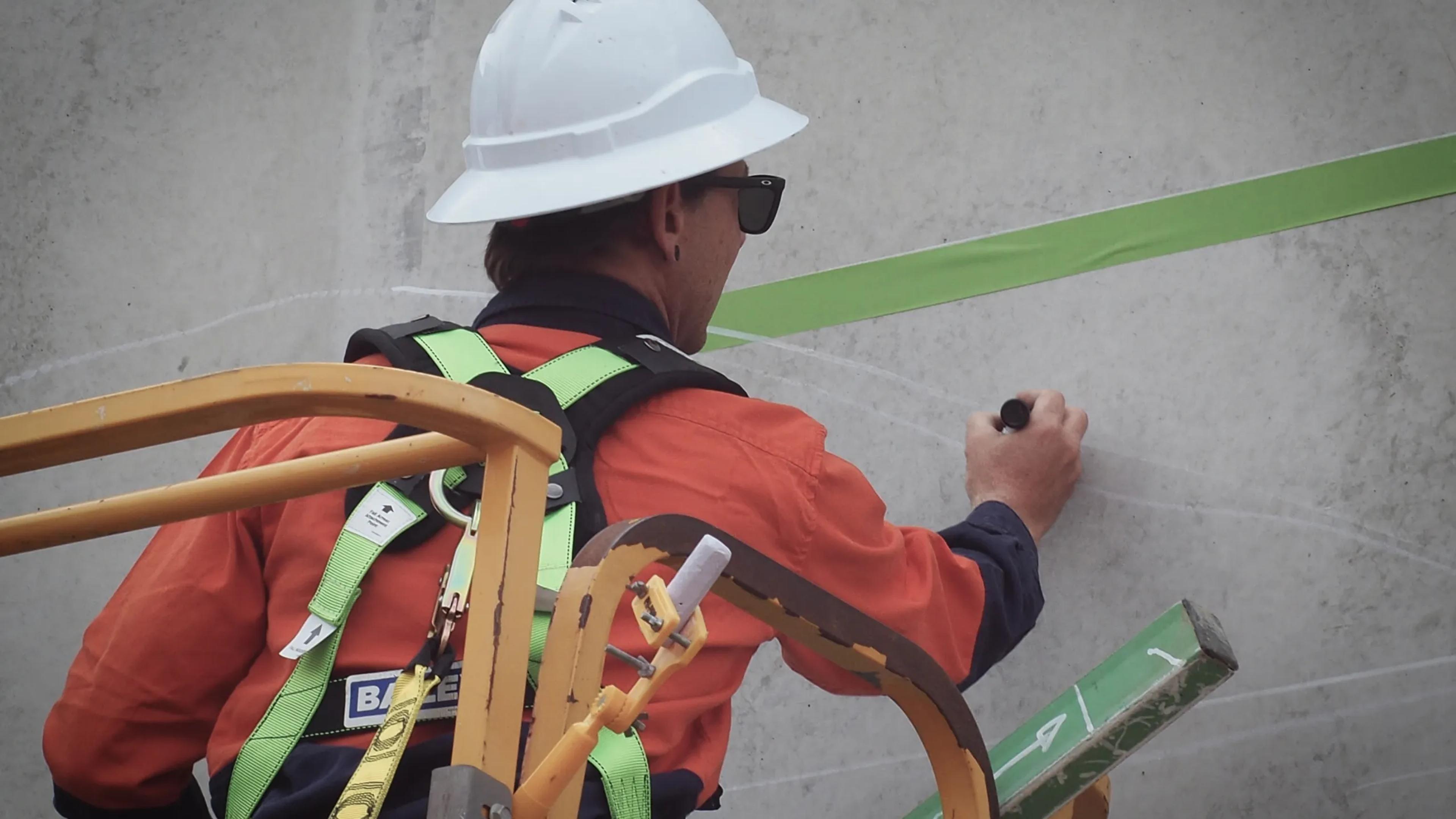A photo of a man drawing a mural on a wall.
