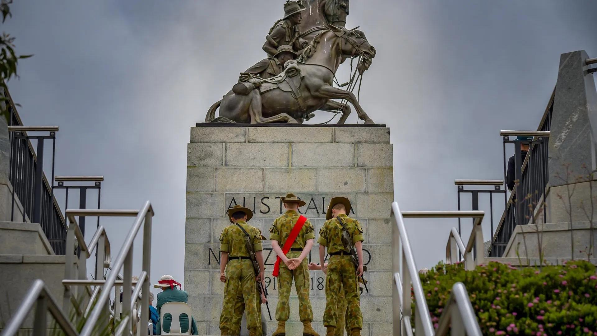 A photo of some soldiers standing in front of an ANZAC memorial.