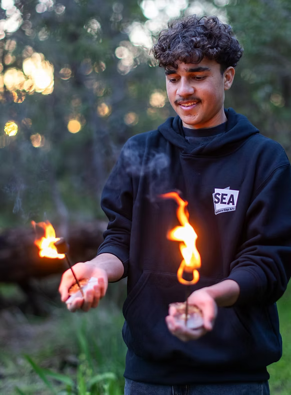 A teenager holds fire in his open palms.