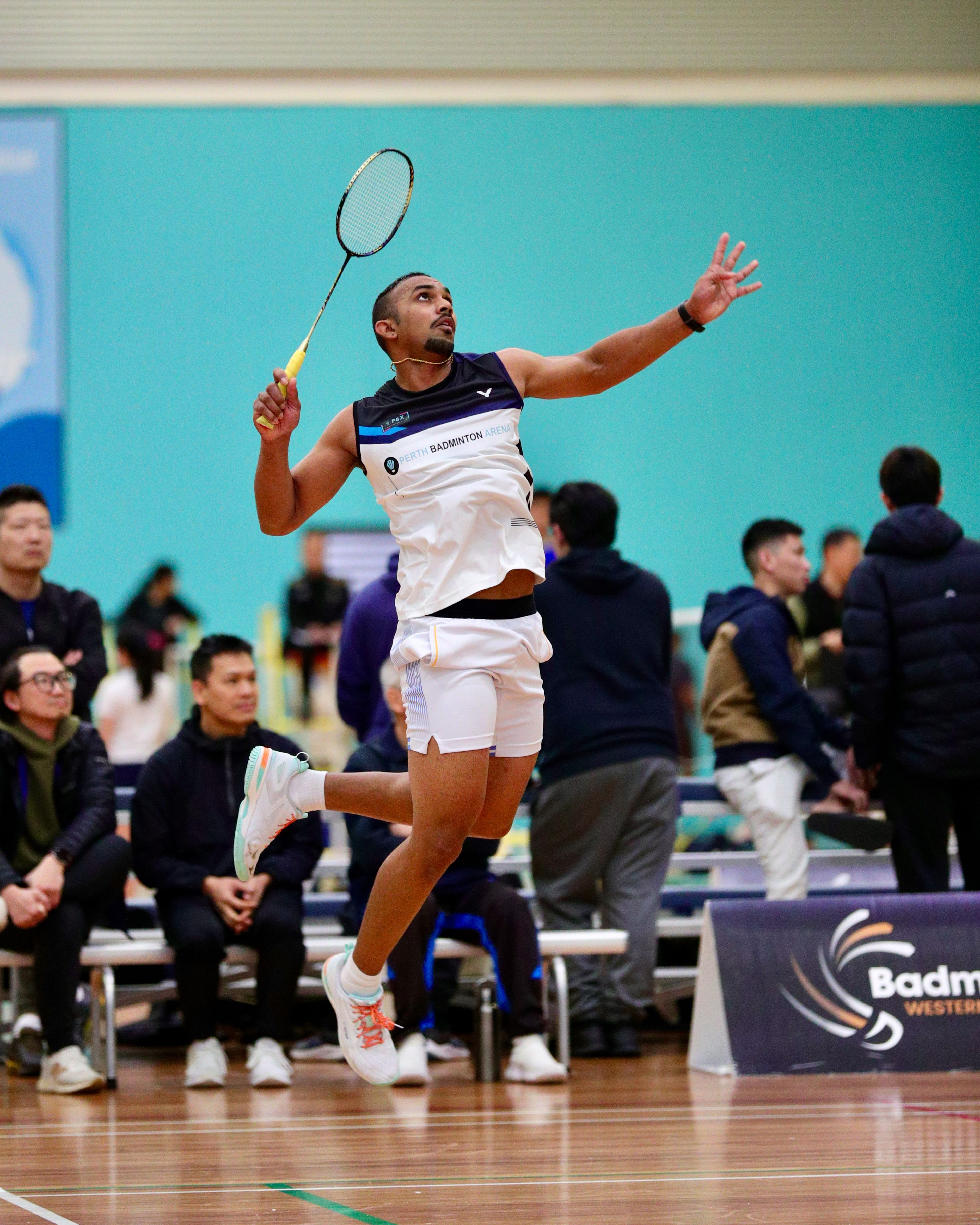 Badminton player Eveshgaran Vasigaran jumps for the shuttlecock.
