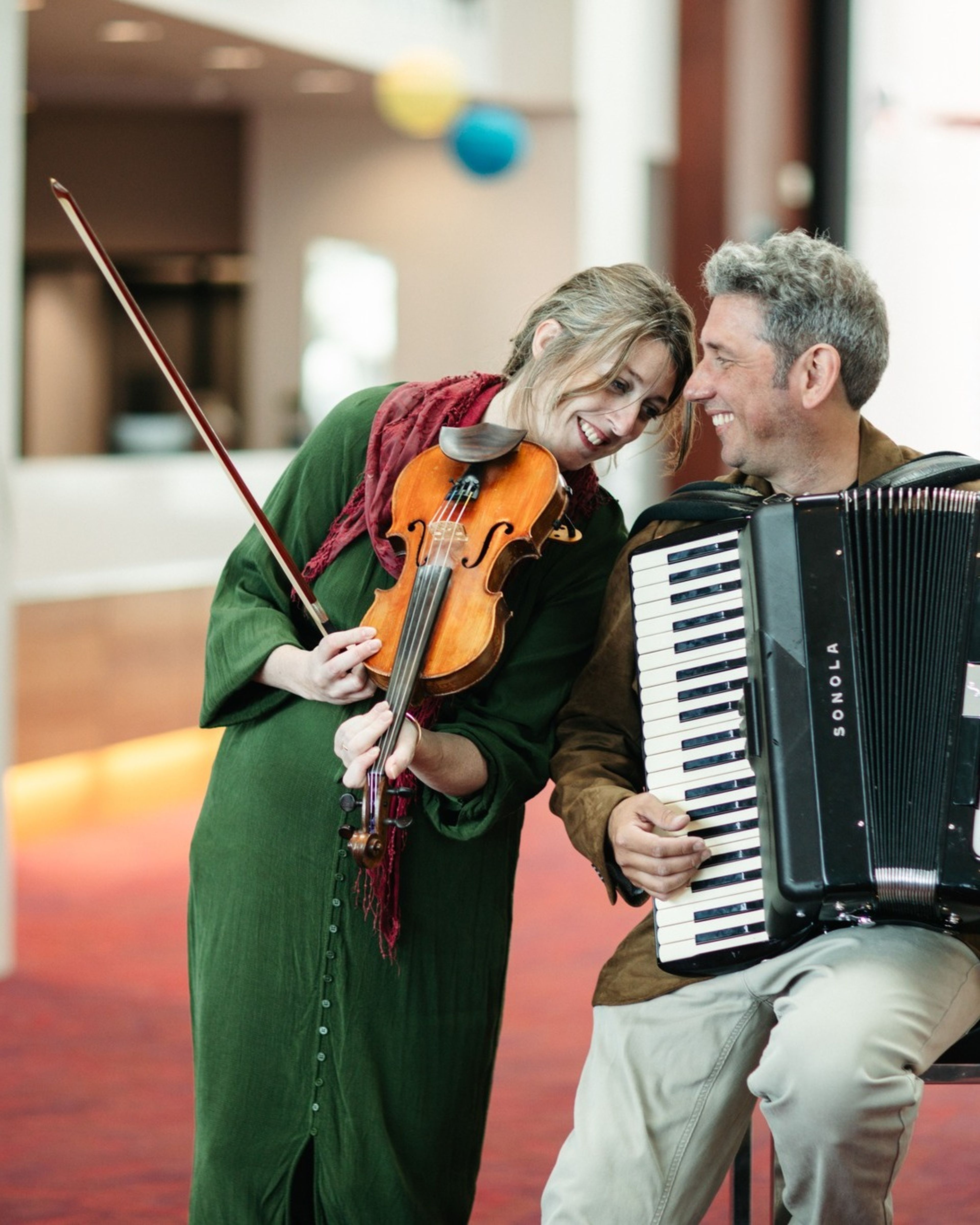 a violin player and an accordion player look to each other