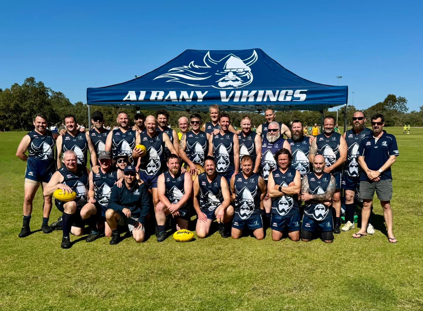 Vikings AFL team gathered for a team photo under a branded marquee