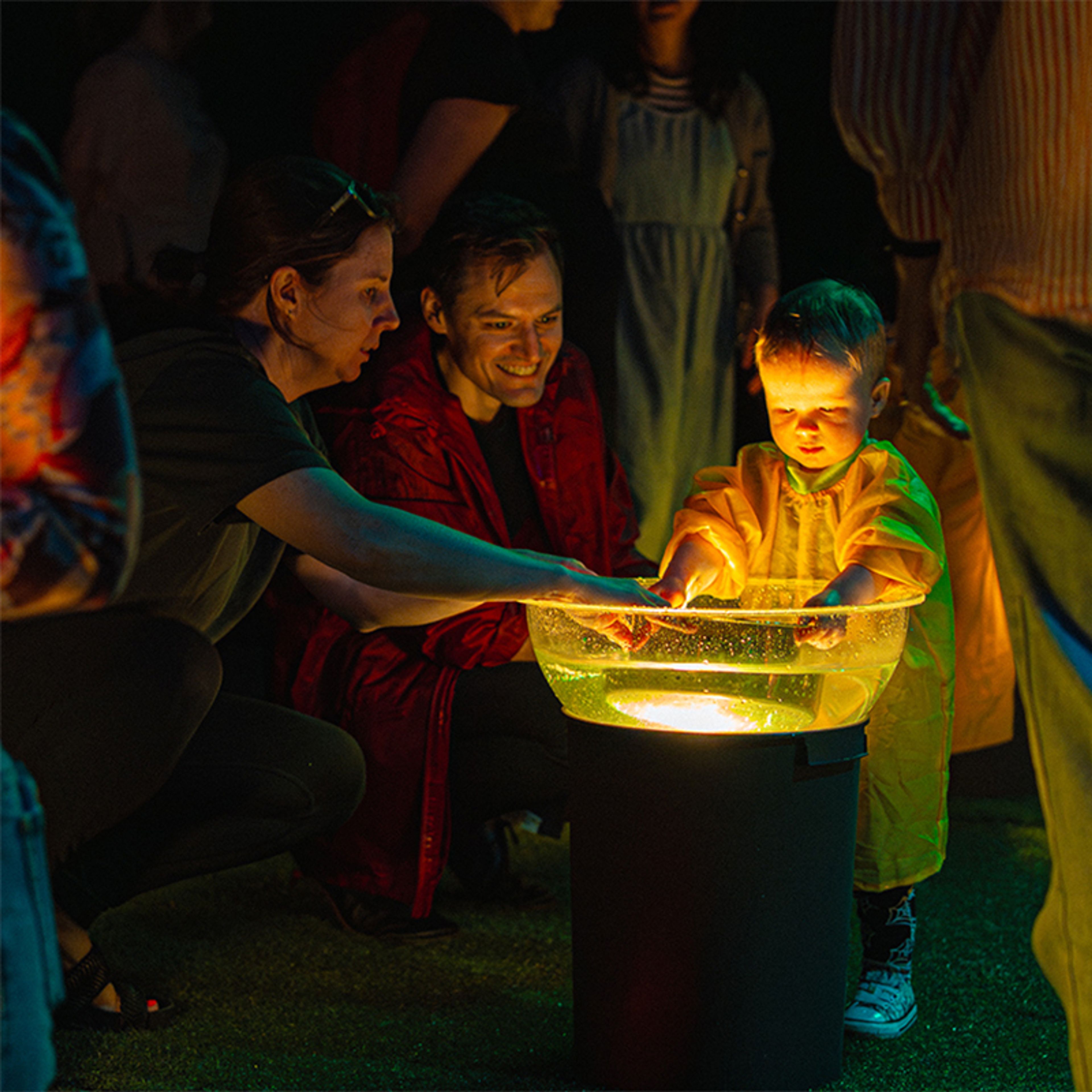 Child and parents interacting with illuminated bowl of water